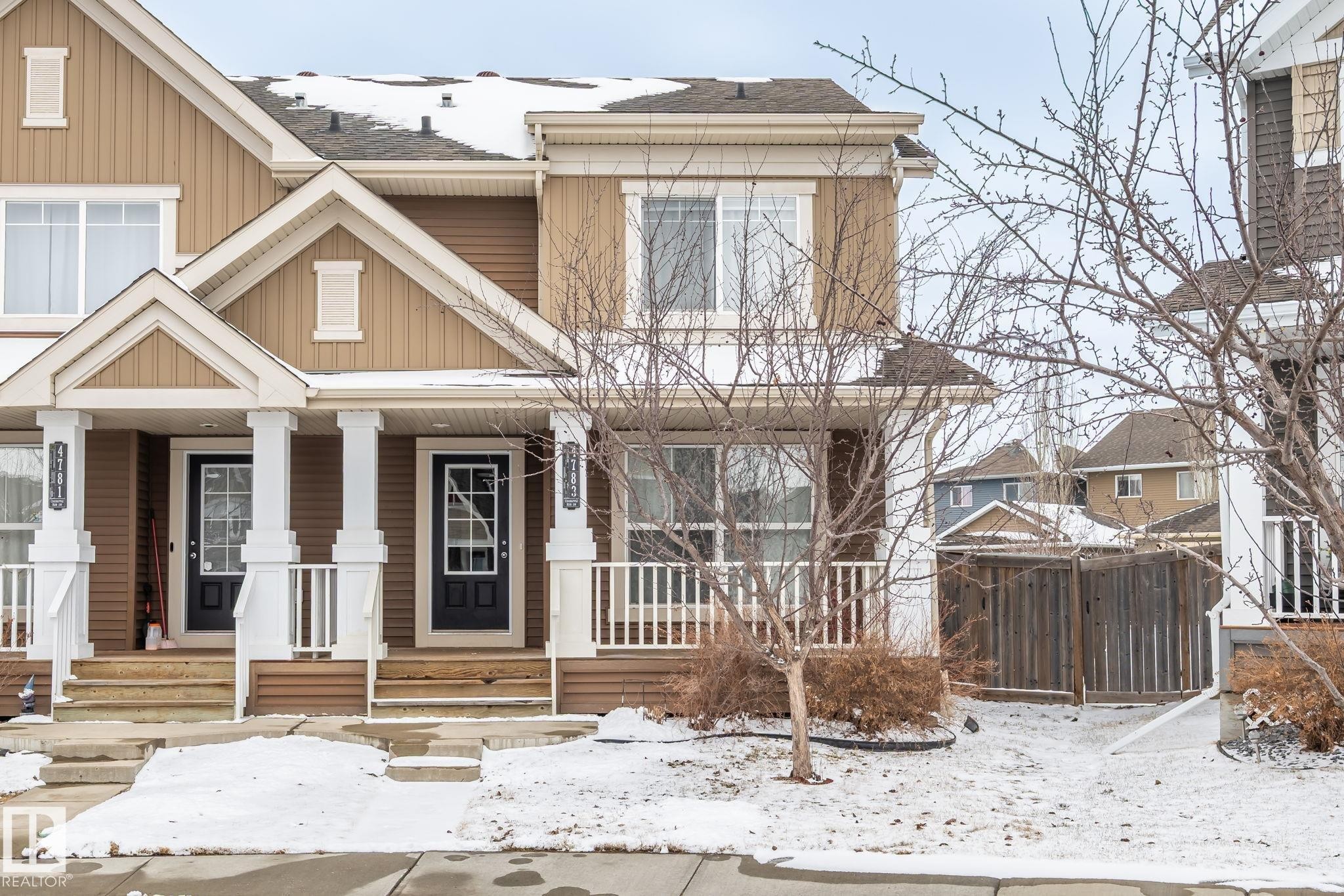 This property features a two-story exterior with a warm, neutral color palette, white trim, and a prominent front porch with white columns and railings - 4783 Crabapplle Run, Edmonton, AB - Outdoor With Facade