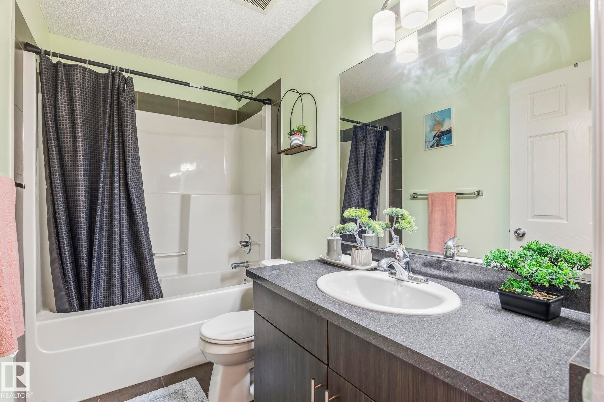 Bathroom featuring a shower and tub combination, a vanity with a white oval sink, and a large mirror - 4783 Crabapplle Run, Edmonton, AB - Indoor Photo Showing Bathroom