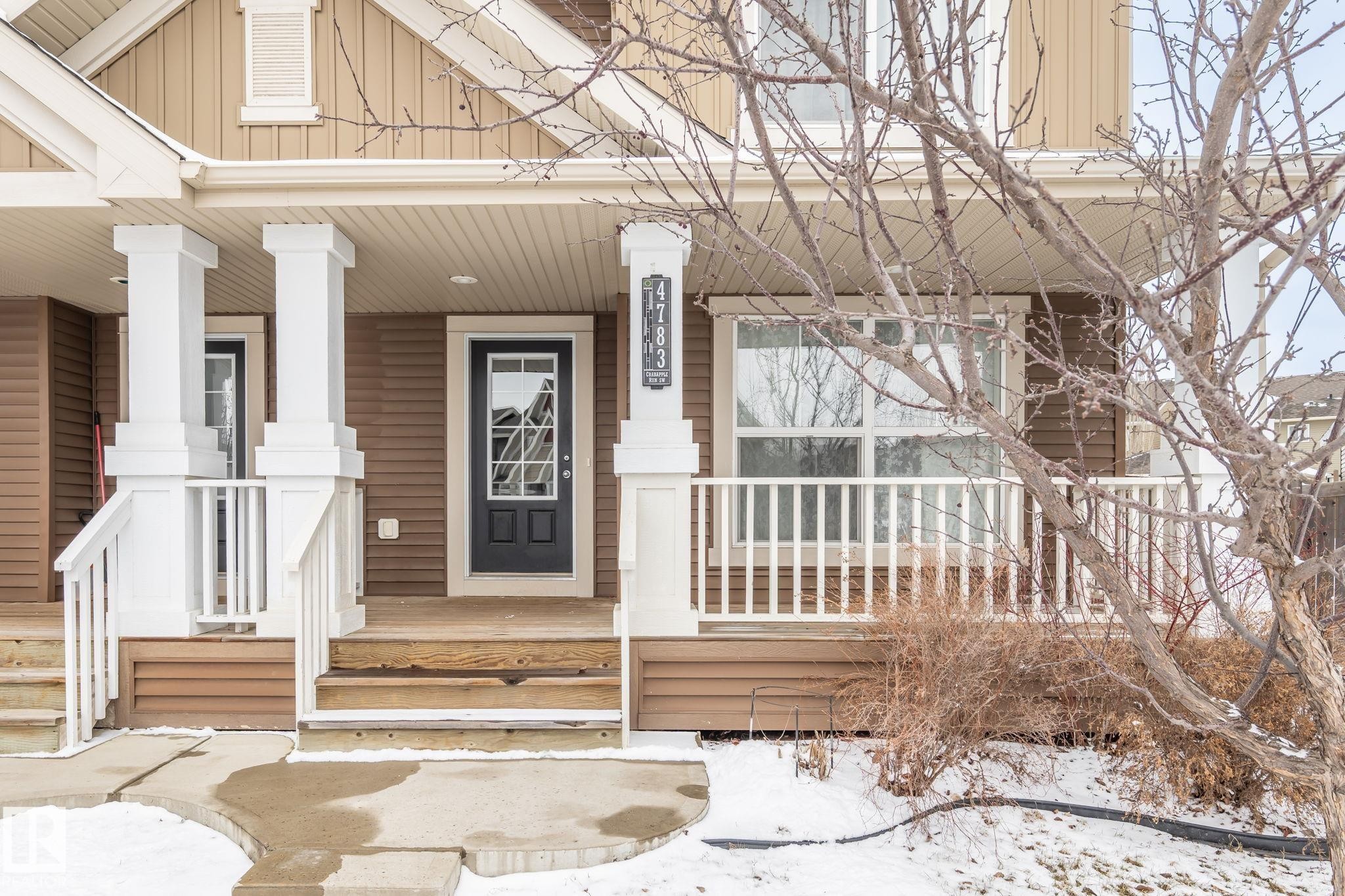 This property features a front porch with white columns and railings, a brown exterior with white trim, and a prominent front door with glass panels - 4783 Crabapplle Run, Edmonton, AB - Outdoor