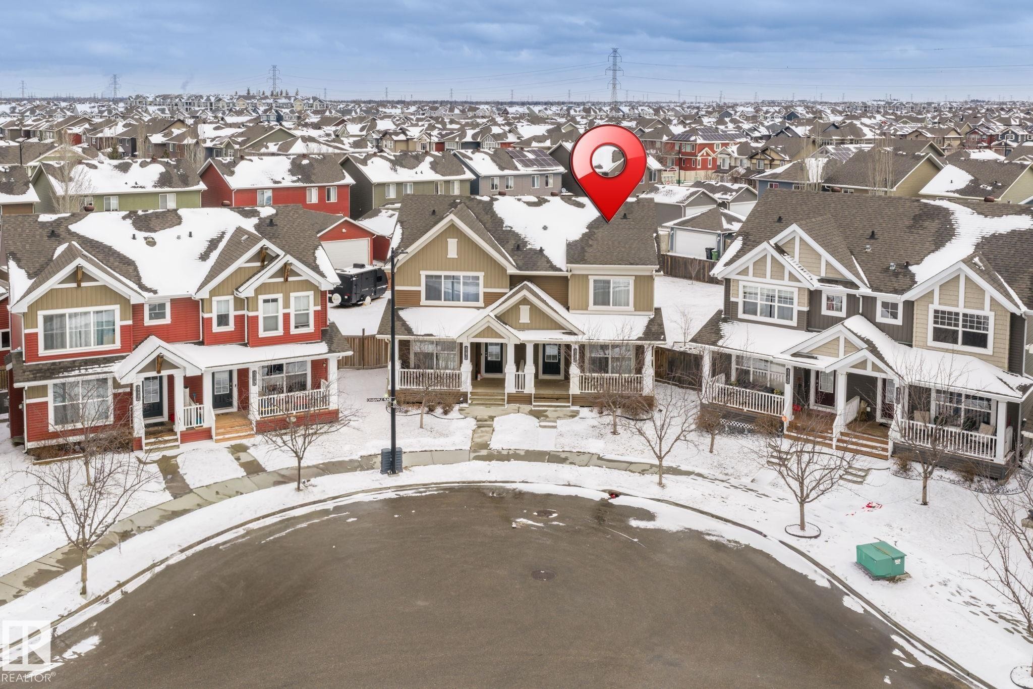 The property is a two-story home with a light brown exterior and a dark roof, featuring a covered front porch and a front-facing attached garage - 4783 Crabapplle Run, Edmonton, AB - Outdoor With Facade