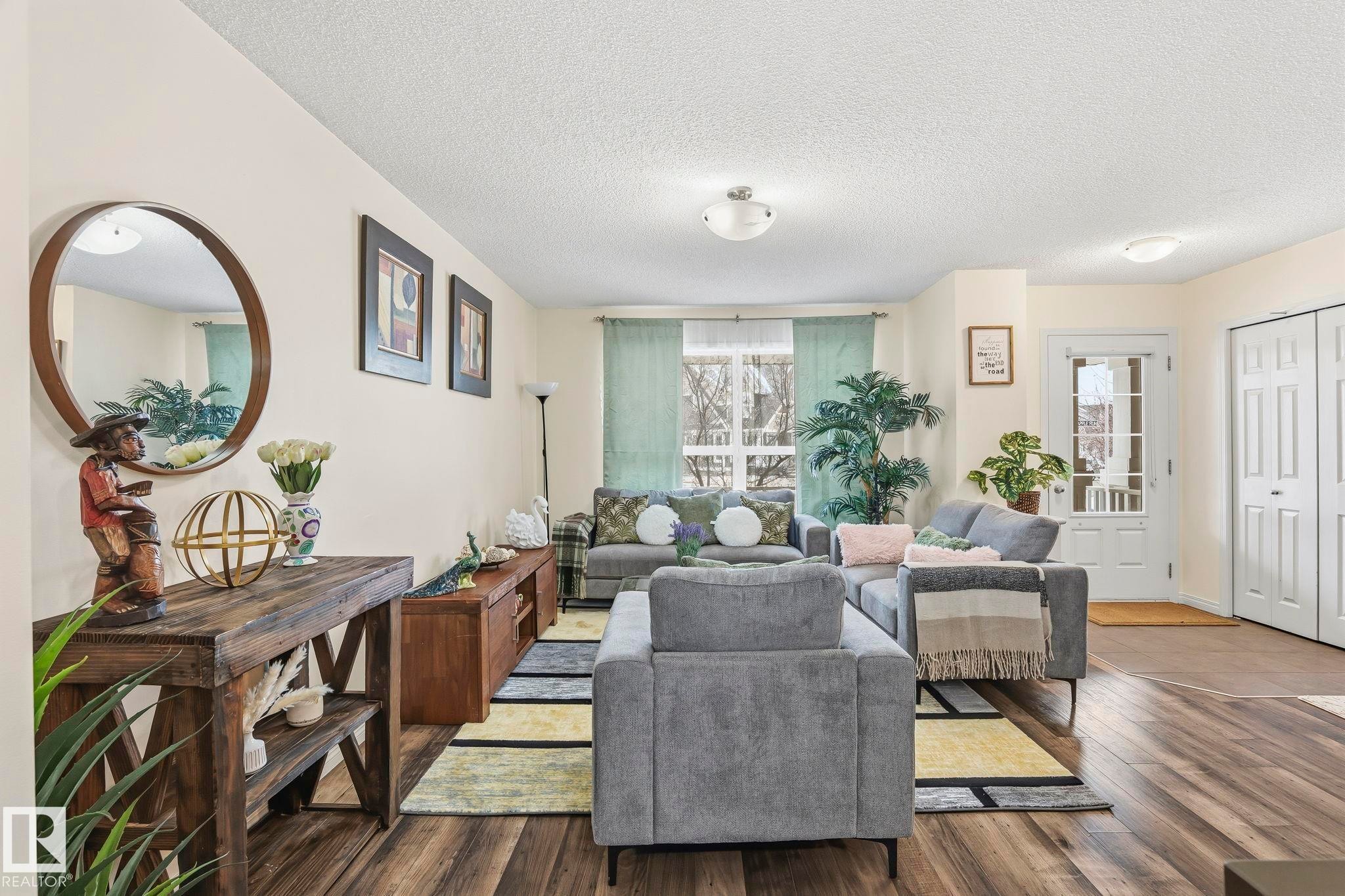 Living area featuring wood-style flooring, light-colored walls, and a window with light-colored curtains - 4783 Crabapplle Run, Edmonton, AB - Indoor Photo Showing Living Room