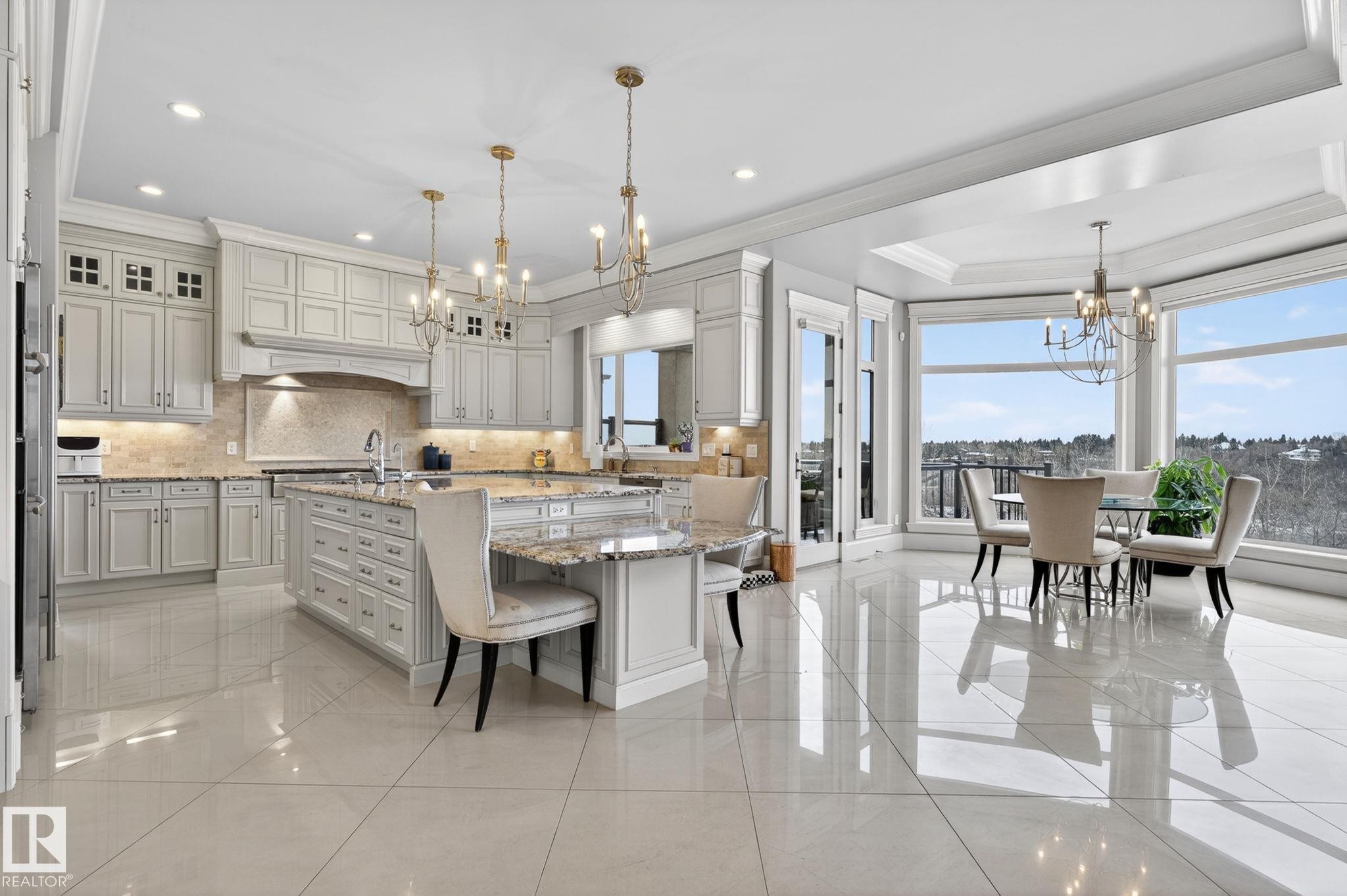Spacious kitchen and dining area featuring light-toned cabinetry, granite countertops, an island with seating, polished tile flooring, and large windows offering expansive views - 1413 Woodward Crescent, Edmonton, AB - Indoor