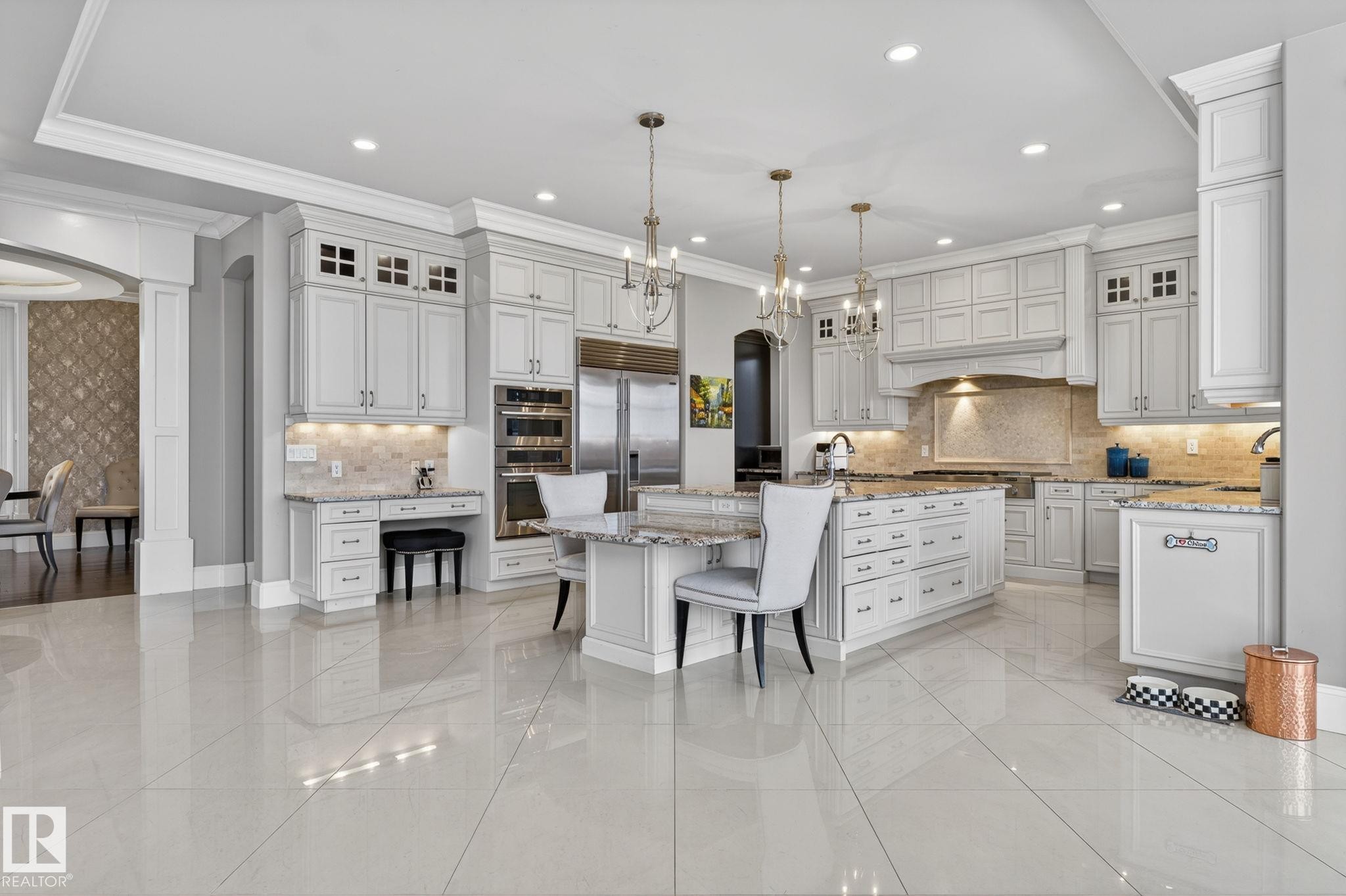 This spacious kitchen features light-colored cabinetry, a large central island with seating, stainless steel appliances, and polished tile flooring - 1413 Woodward Crescent, Edmonton, AB - Indoor Photo Showing Kitchen With Upgraded Kitchen