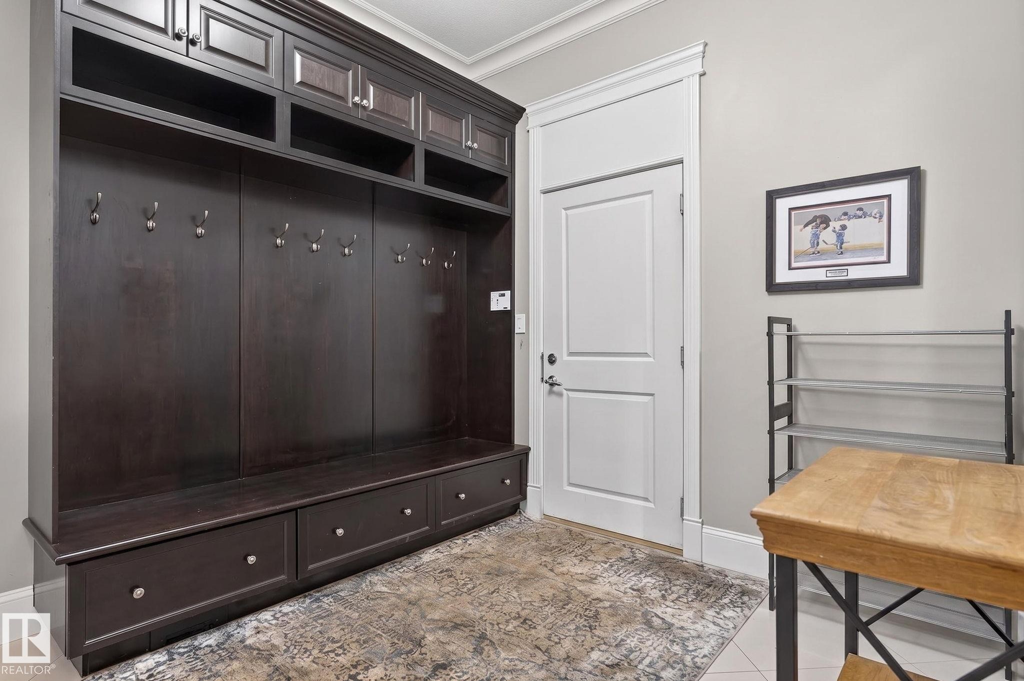 Entry area featuring dark wood built-in storage with hooks and drawers, a white door, and light-colored walls - 1413 Woodward Crescent, Edmonton, AB - Indoor Photo Showing Other Room