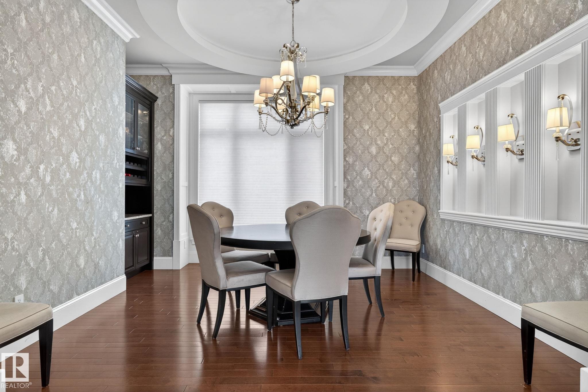 This dining area features hardwood floors, decorative wallpaper, and a recessed ceiling with a chandelier - 1413 Woodward Crescent, Edmonton, AB - Indoor Photo Showing Dining Room