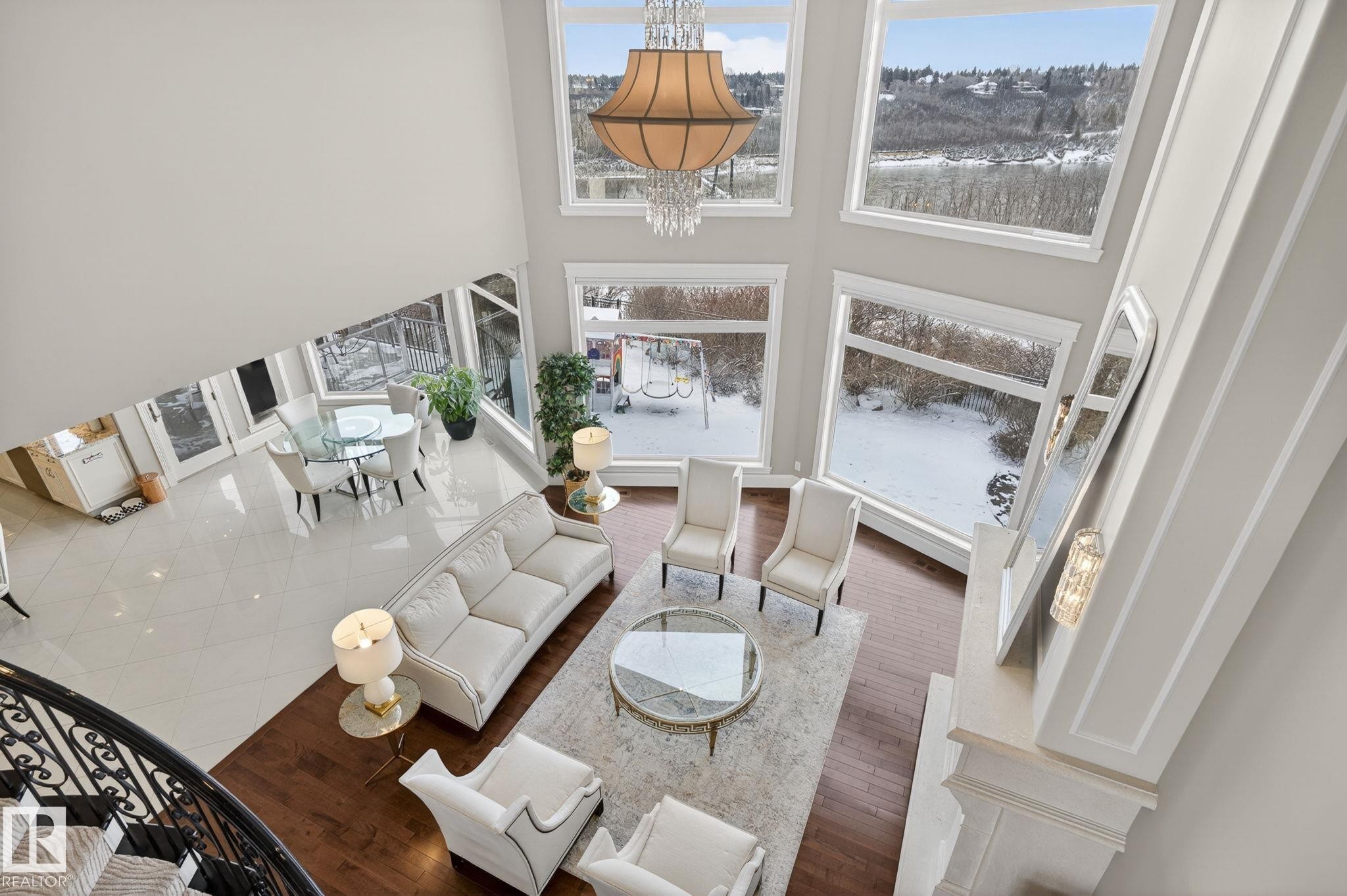 This bright and airy living area boasts high ceilings, hardwood flooring, and a grand chandelier - 1413 Woodward Crescent, Edmonton, AB - Indoor Photo Showing Other Room