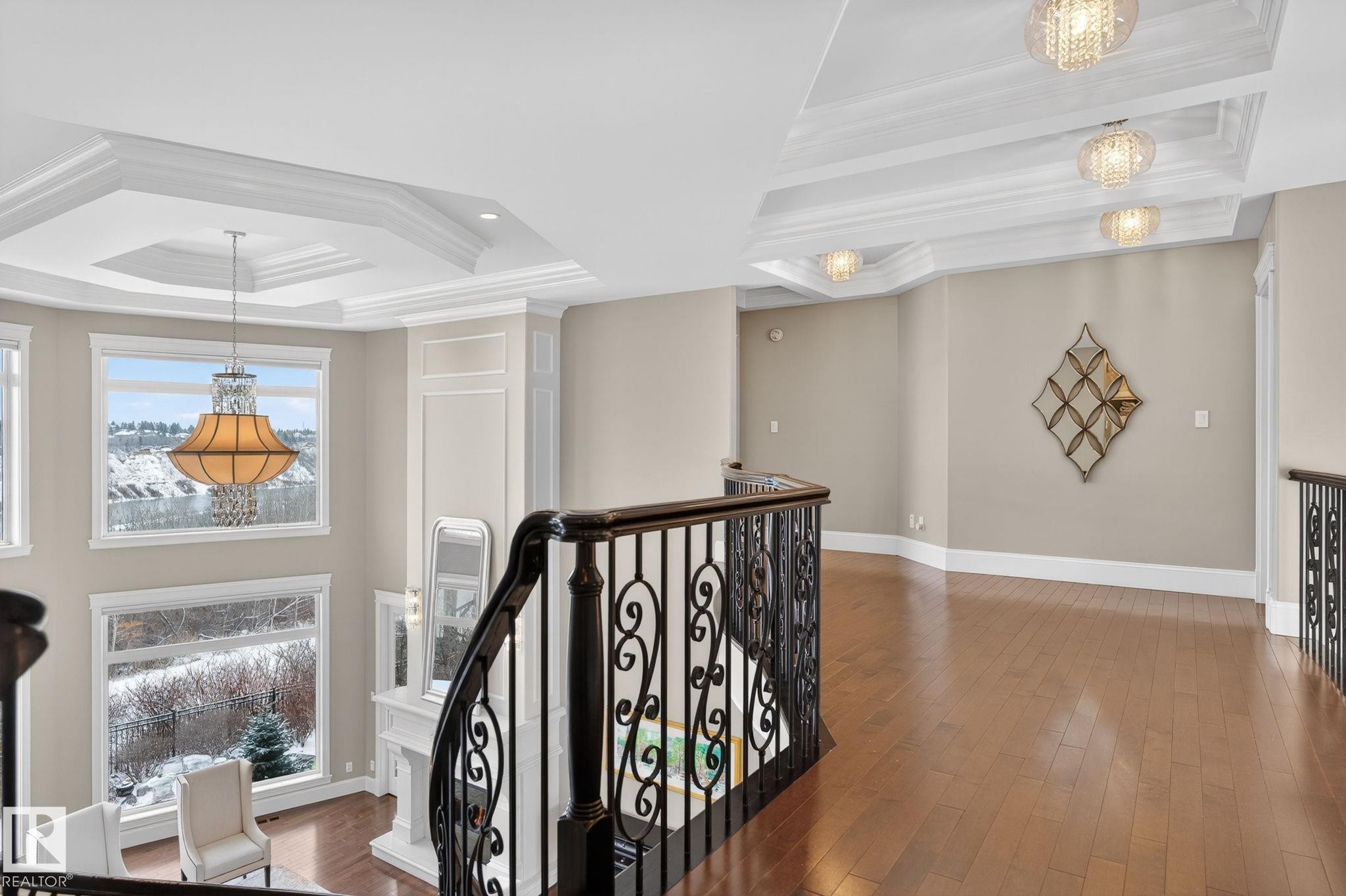 The property features an open landing with hardwood flooring, decorative iron railings, and large windows providing views of the surrounding area - 1413 Woodward Crescent, Edmonton, AB - Indoor Photo Showing Other Room