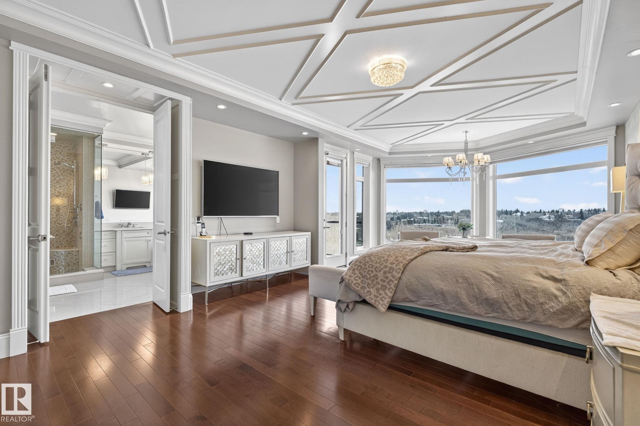 This room features hardwood flooring, a coffered ceiling with a chandelier, and large windows offering expansive views - 1413 Woodward Crescent, Edmonton, AB - Indoor Photo Showing Bedroom