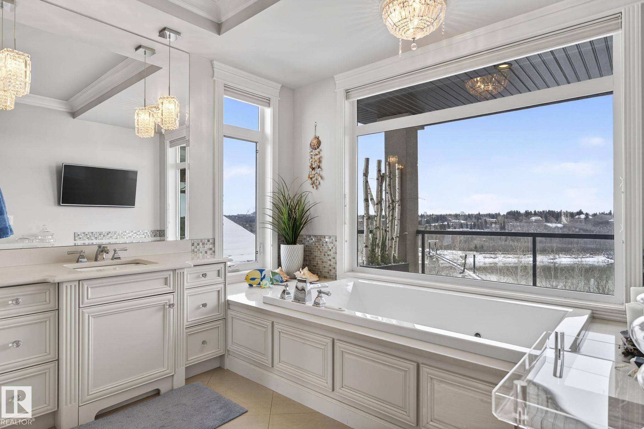 Elegant bathroom featuring a spacious built-in tub, a large window offering expansive outdoor views, and a vanity with an integrated sink and mirror - 1413 Woodward Crescent, Edmonton, AB - Indoor Photo Showing Bathroom