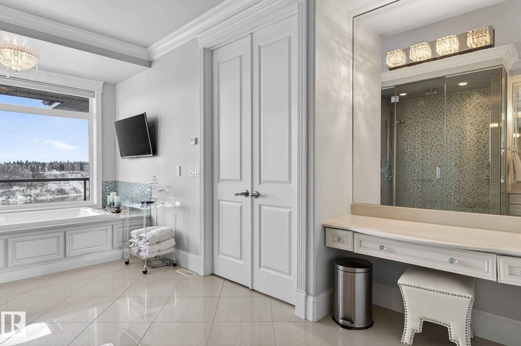 The bathroom features a built-in bathtub with a large window, a spacious vanity with a mirror and decorative lighting, and a glass-enclosed shower with tiled walls - 1413 Woodward Crescent, Edmonton, AB - Indoor Photo Showing Other Room