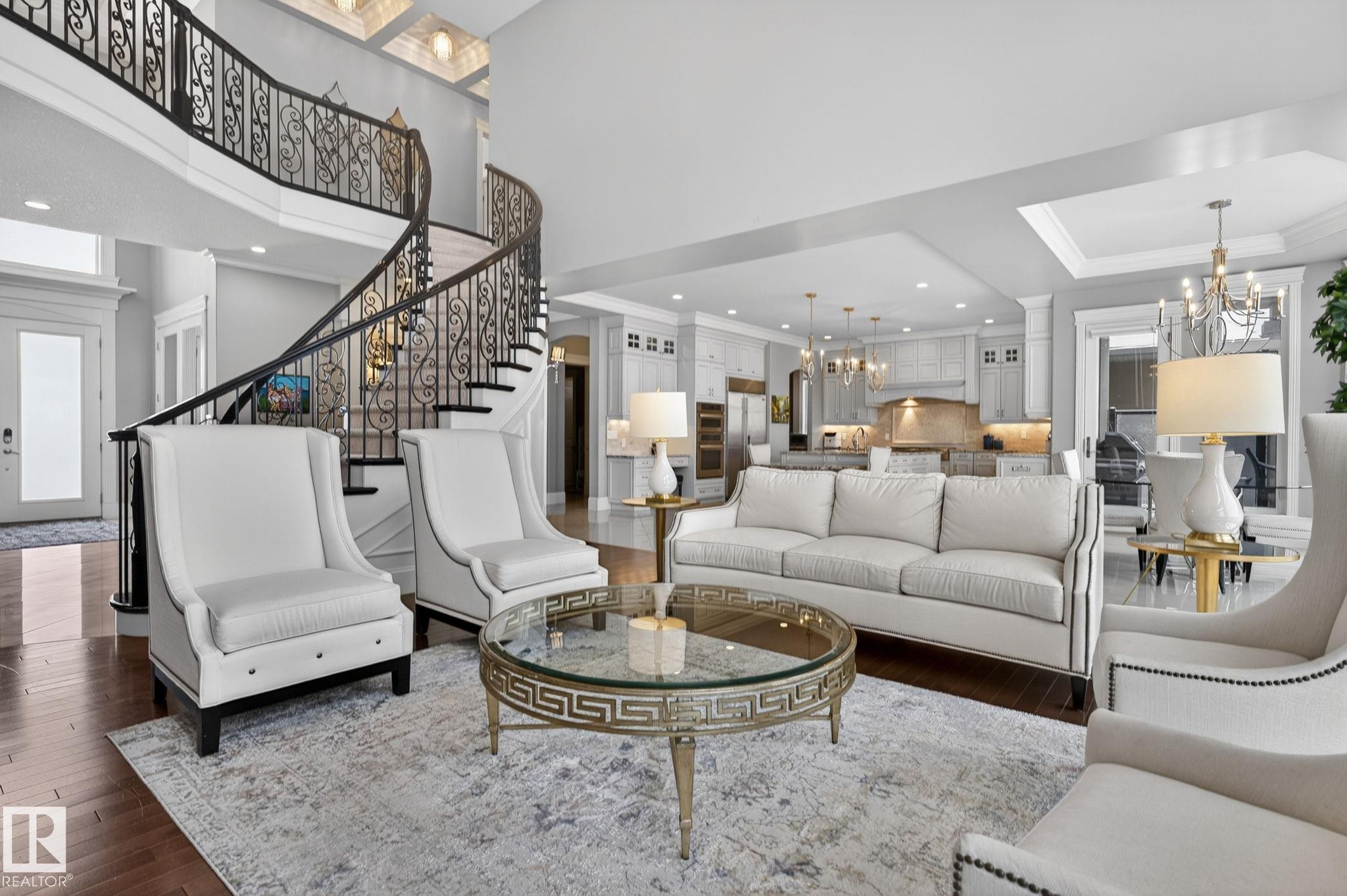 This expansive living space features hardwood flooring, a grand curved staircase with ornate iron railings, and recessed lighting - 1413 Woodward Crescent, Edmonton, AB - Indoor Photo Showing Living Room