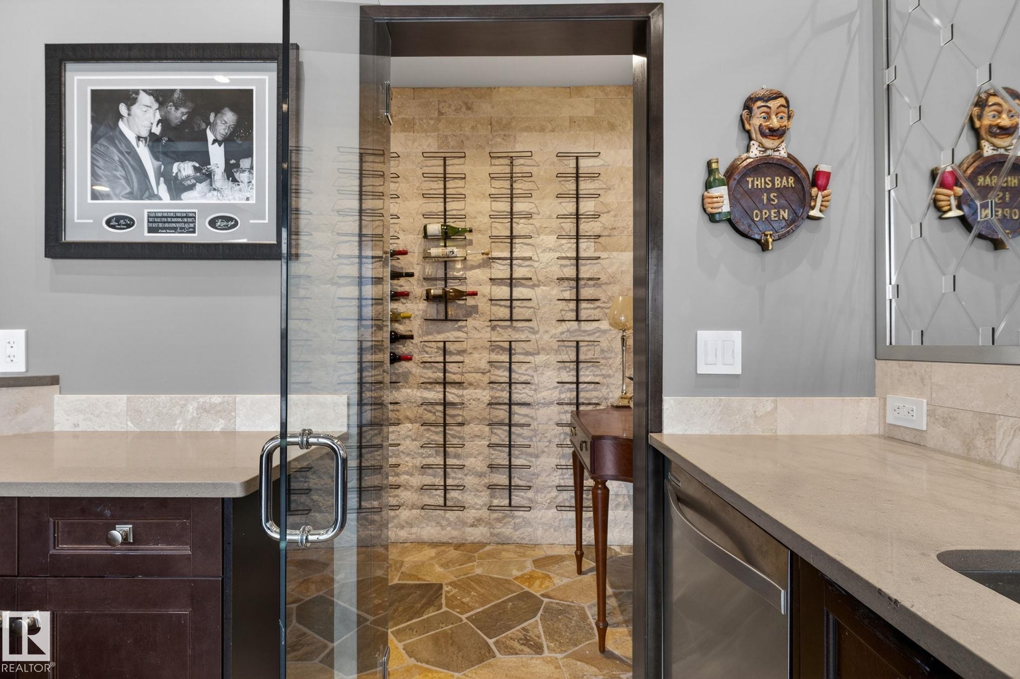 The property features a wine cellar with stone-clad walls and flagstone flooring, accessible through a glass door - 1413 Woodward Crescent, Edmonton, AB - Indoor Photo Showing Kitchen