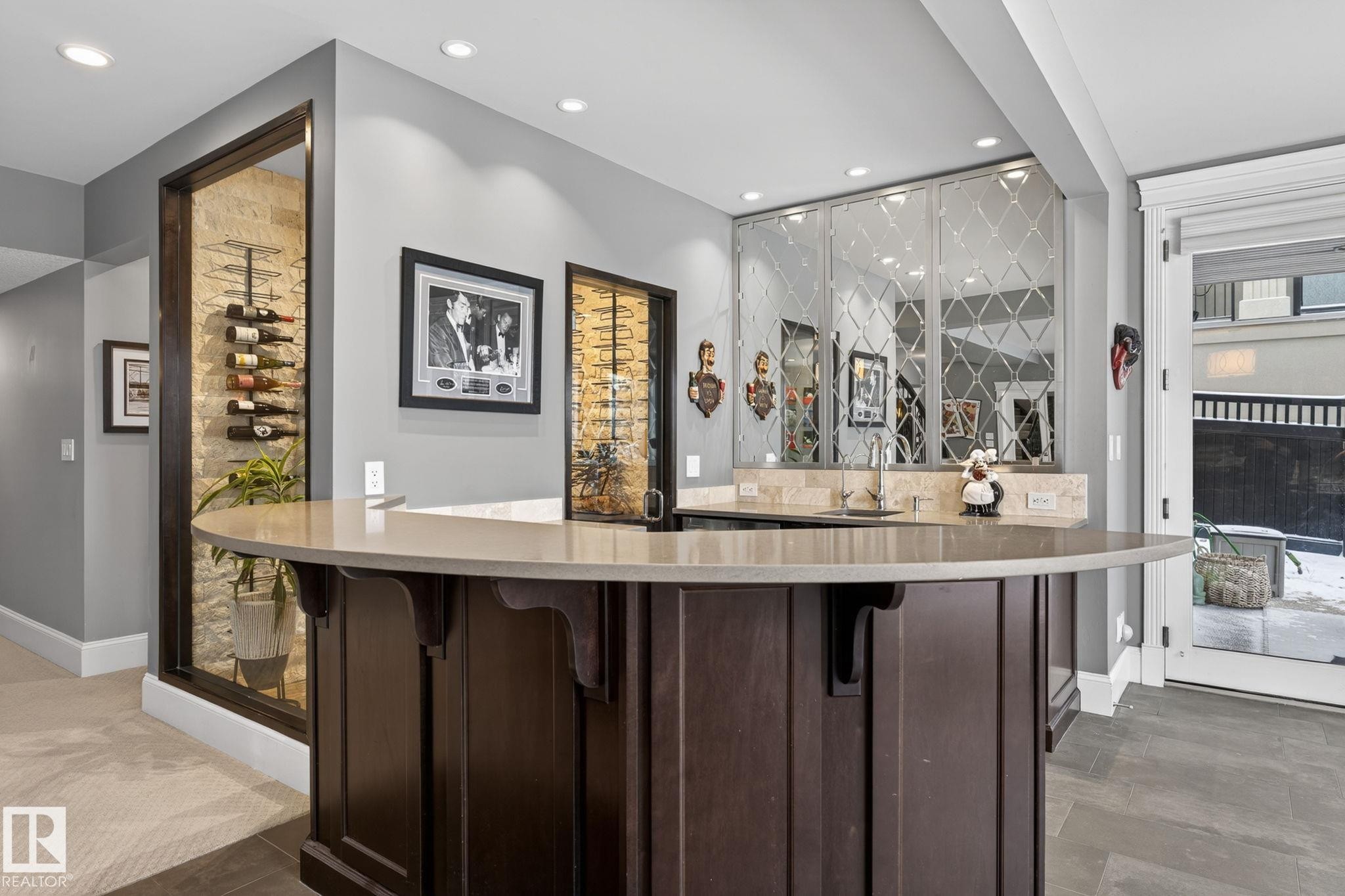 The property features a wet bar with a dark wood base and a light-colored countertop, complemented by a tiled backsplash and mirrored wall accents - 1413 Woodward Crescent, Edmonton, AB - Indoor