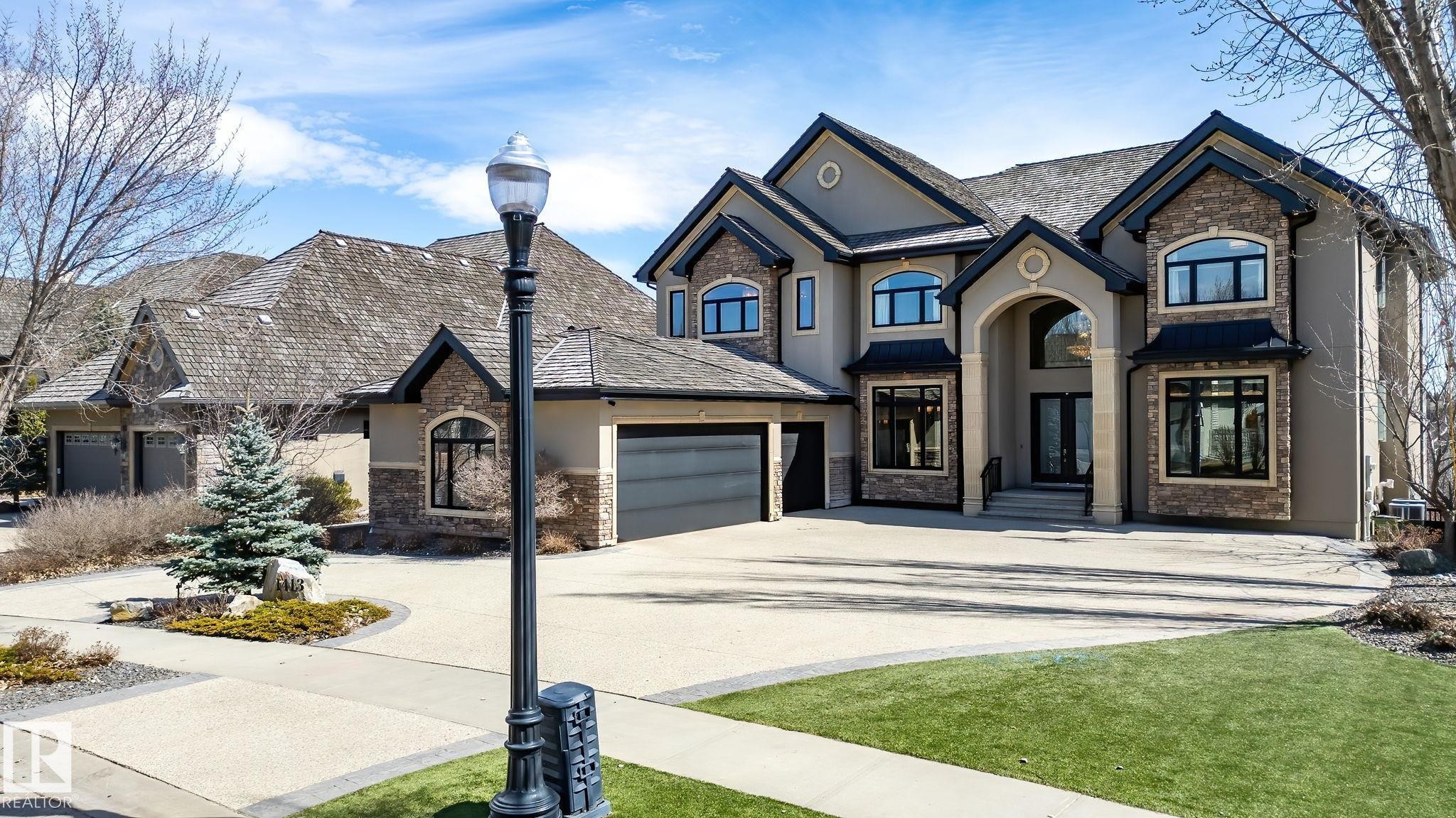 Stately stucco and stone-clad residence featuring a multi-gabled roofline and an arched portico entry - 1413 Woodward Crescent, Edmonton, AB - Outdoor With View
