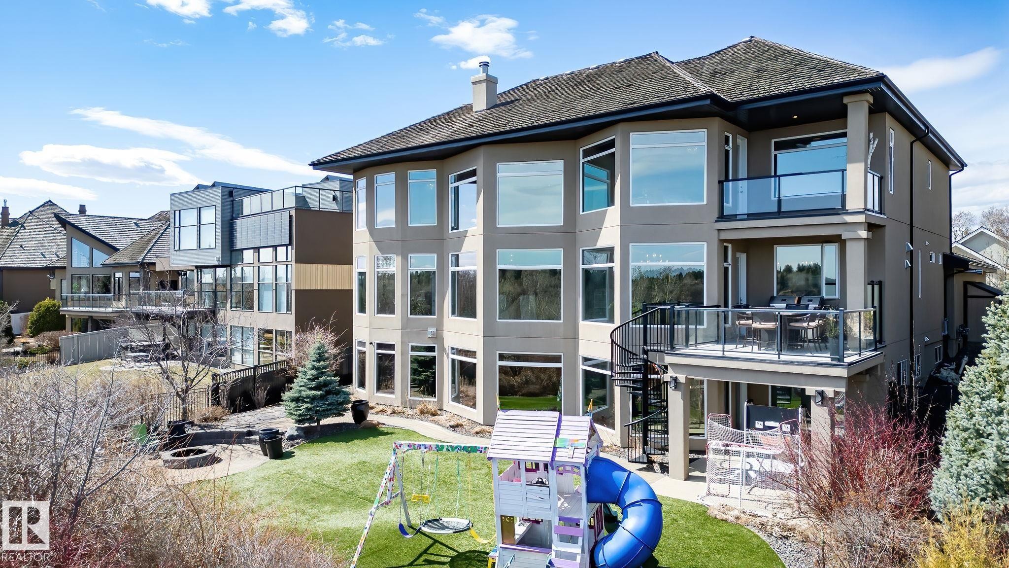 Multi-level rear exterior featuring extensive window arrays, a spiral staircase, and multiple glass-paneled balconies - 1413 Woodward Crescent, Edmonton, AB - Outdoor With Facade