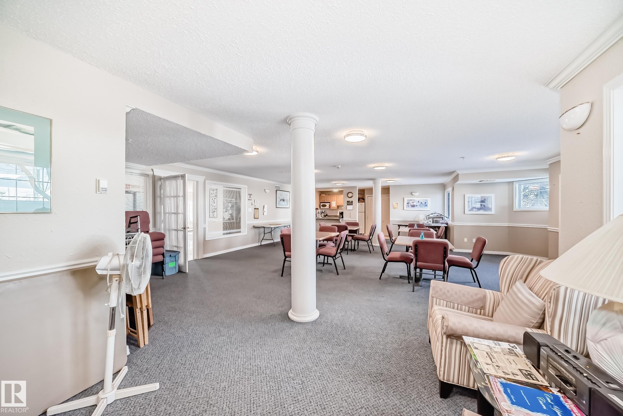 The property features a spacious common area with carpeted flooring, decorative wall sconces, and recessed lighting - 112 17150 94A Avenue, Edmonton, AB - Indoor