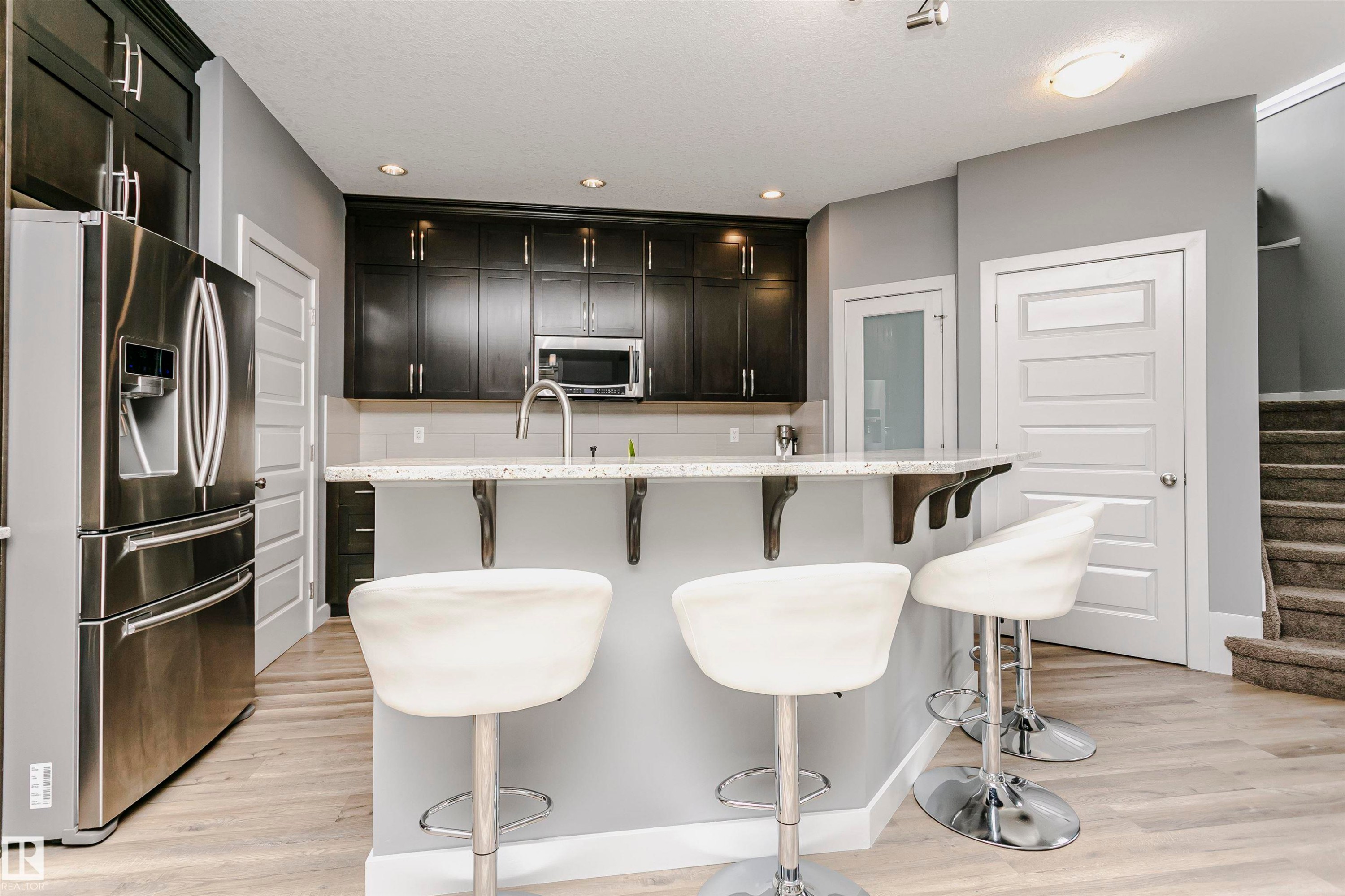 This kitchen features dark cabinetry, stainless steel appliances, and a light-colored countertop - 21807 97 Avenue, Edmonton, AB - Indoor Photo Showing Other Room