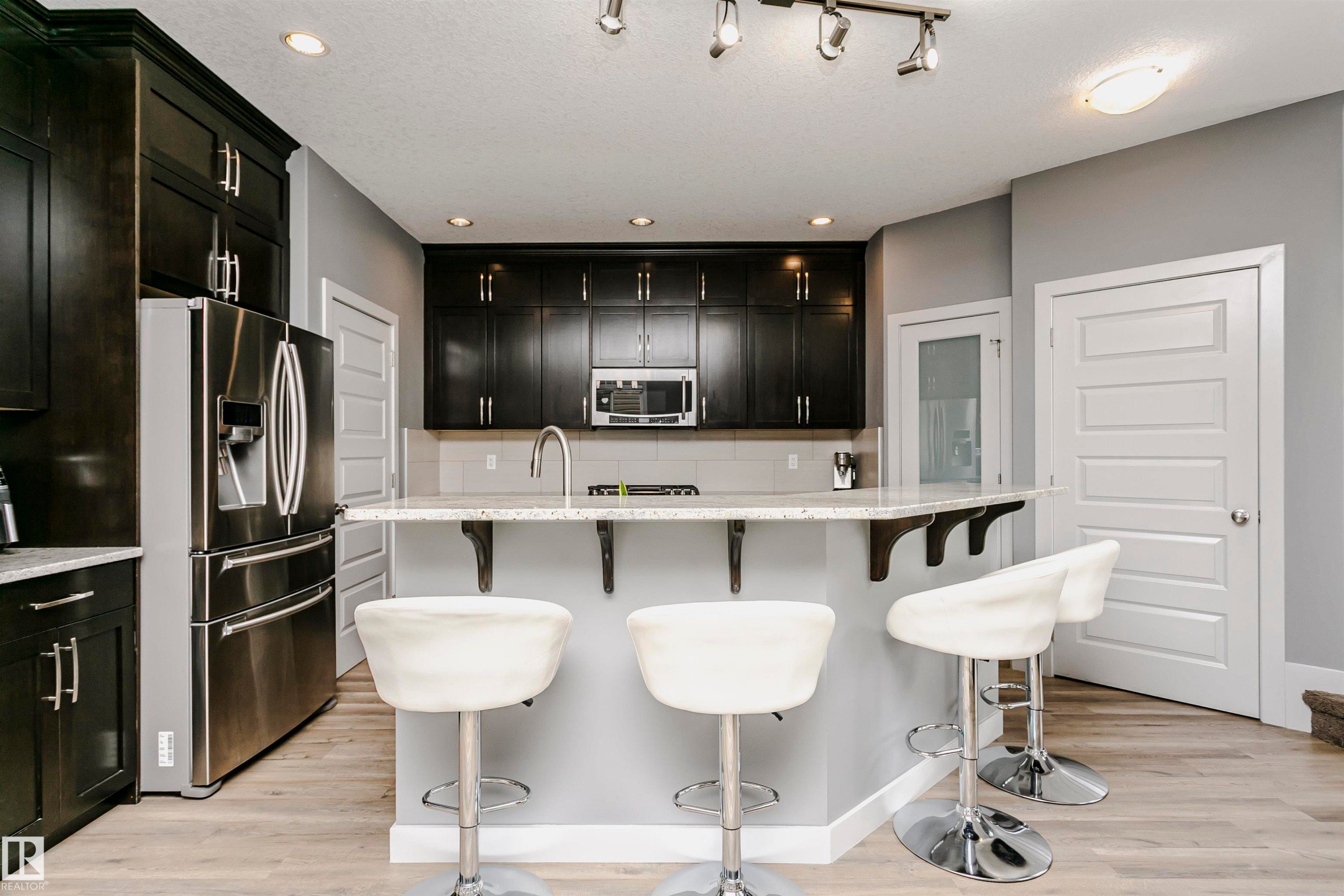 The kitchen features dark cabinetry, stainless steel appliances, and a light-colored countertop with an integrated sink - 21807 97 Avenue, Edmonton, AB - Indoor Photo Showing Kitchen With Upgraded Kitchen