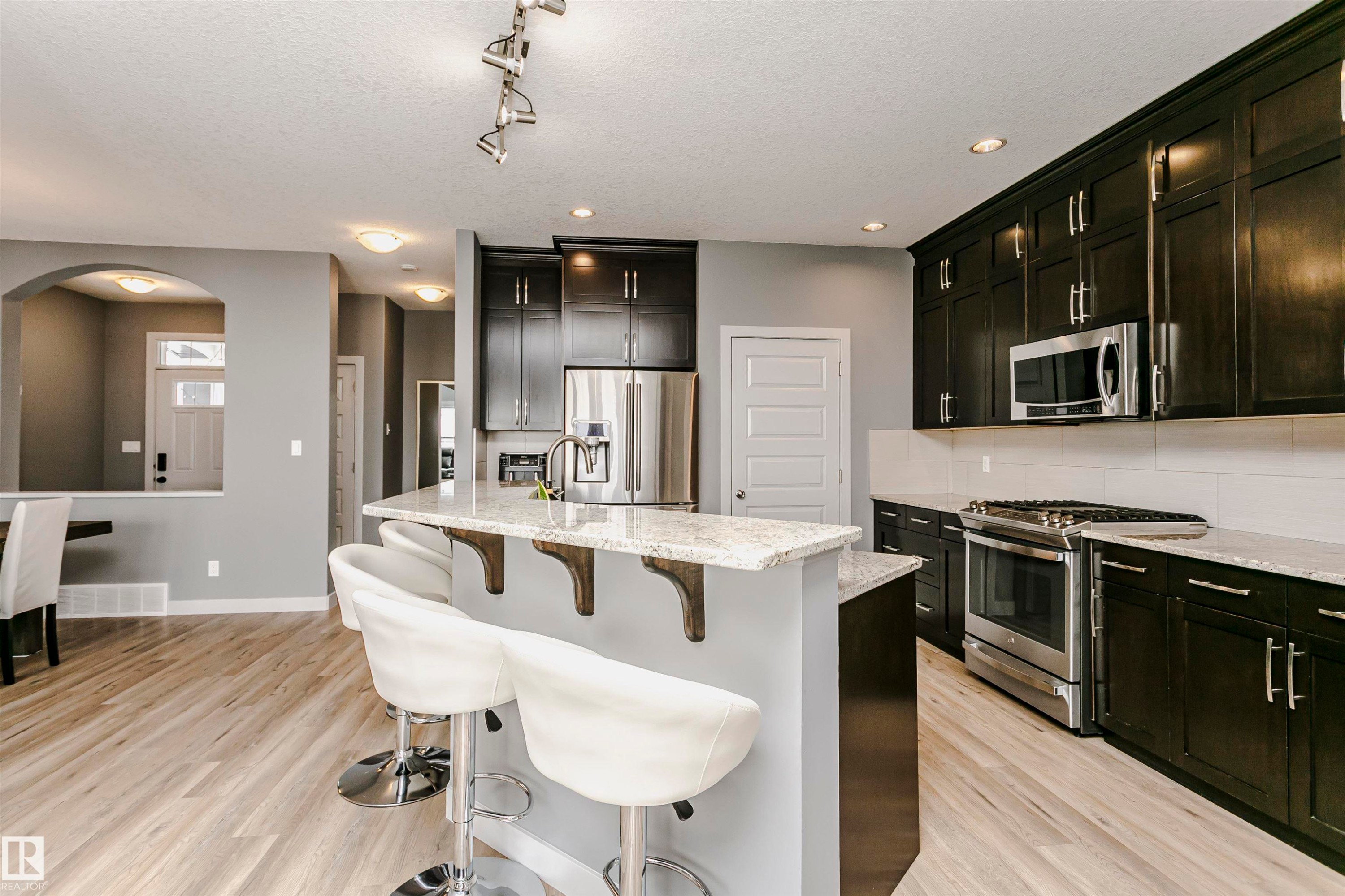 The kitchen features dark cabinetry, stainless steel appliances, and light granite countertops with a white subway tile backsplash - 21807 97 Avenue, Edmonton, AB - Indoor Photo Showing Kitchen With Upgraded Kitchen
