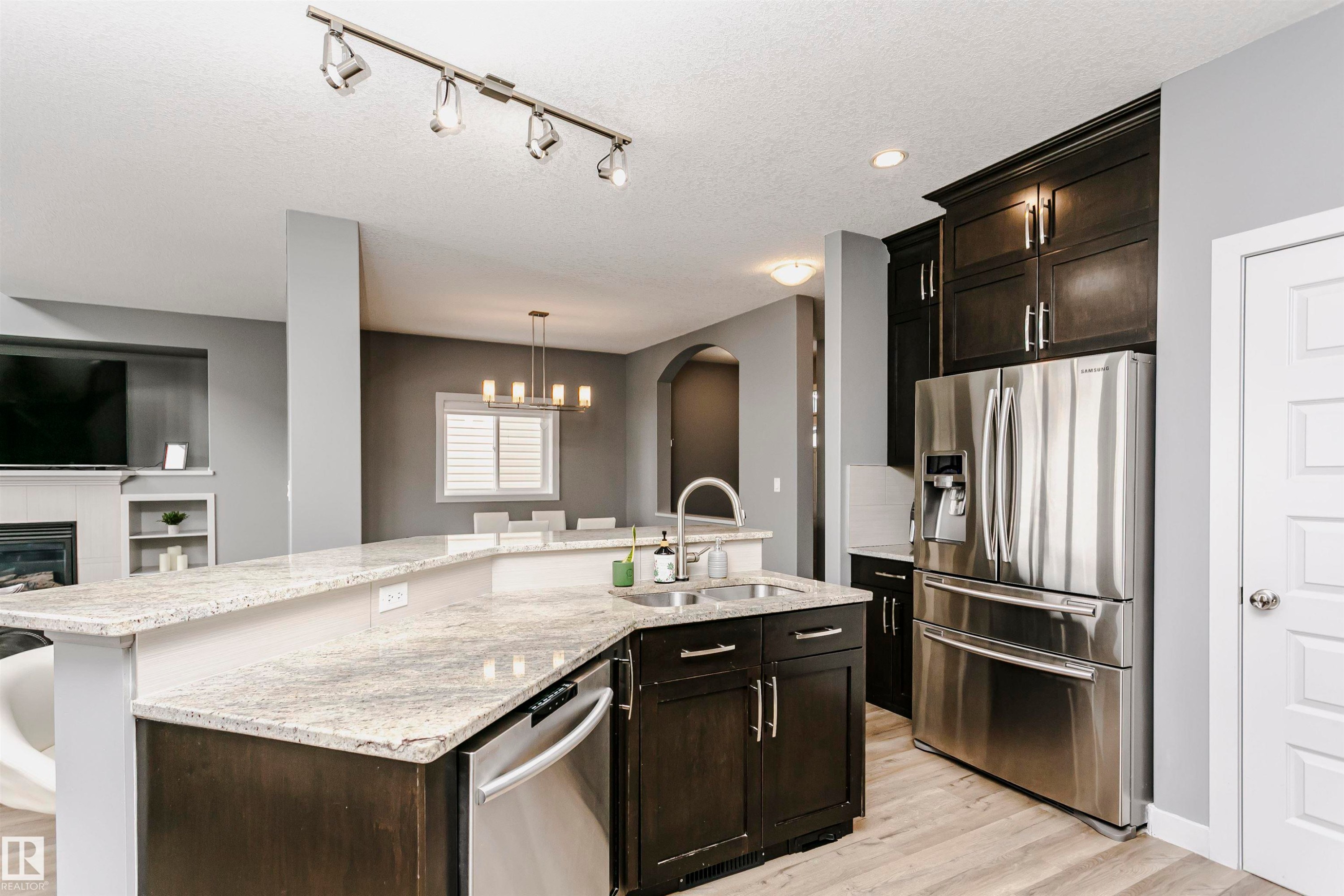 The kitchen features dark cabinetry, light-colored granite countertops, and stainless steel appliances - 21807 97 Avenue, Edmonton, AB - Indoor Photo Showing Kitchen With Double Sink With Upgraded Kitchen