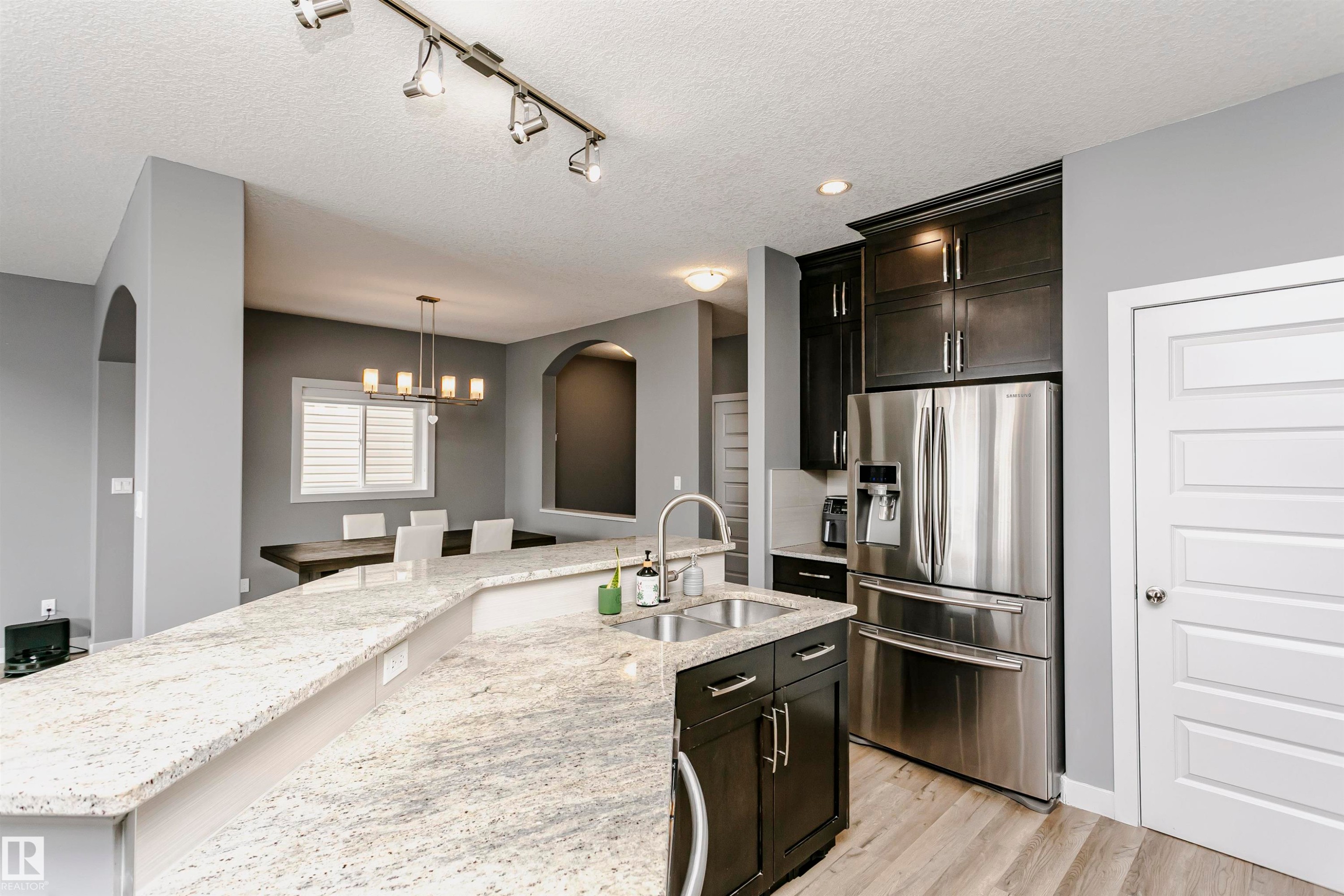 Kitchen with granite countertops, dark wood cabinetry, stainless steel appliances, and wood-style flooring - 21807 97 Avenue, Edmonton, AB - Indoor Photo Showing Kitchen With Double Sink