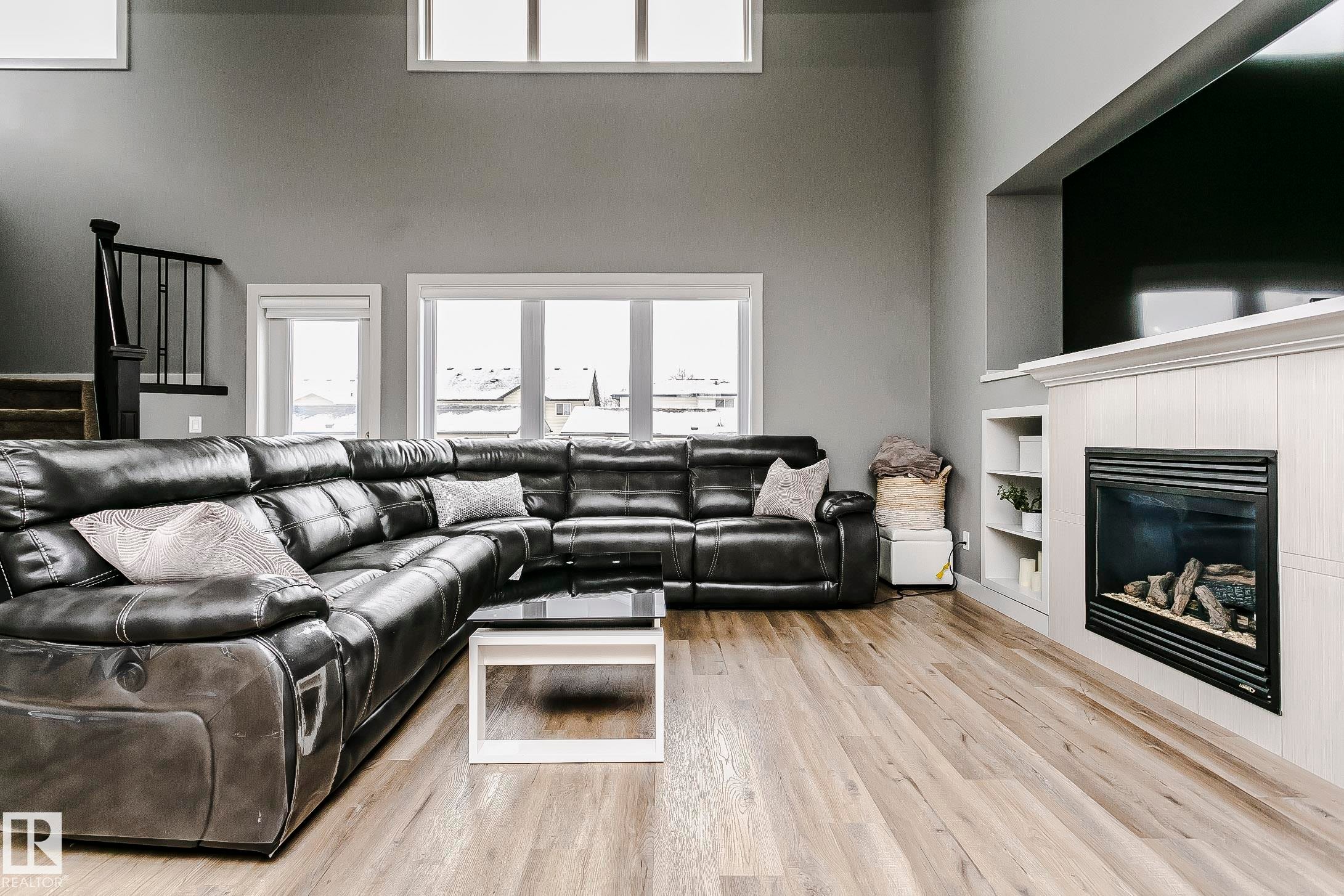 Living area featuring light wood-style flooring, a built-in fireplace with a white mantel, and windows providing natural light - 21807 97 Avenue, Edmonton, AB - Indoor Photo Showing Living Room With Fireplace