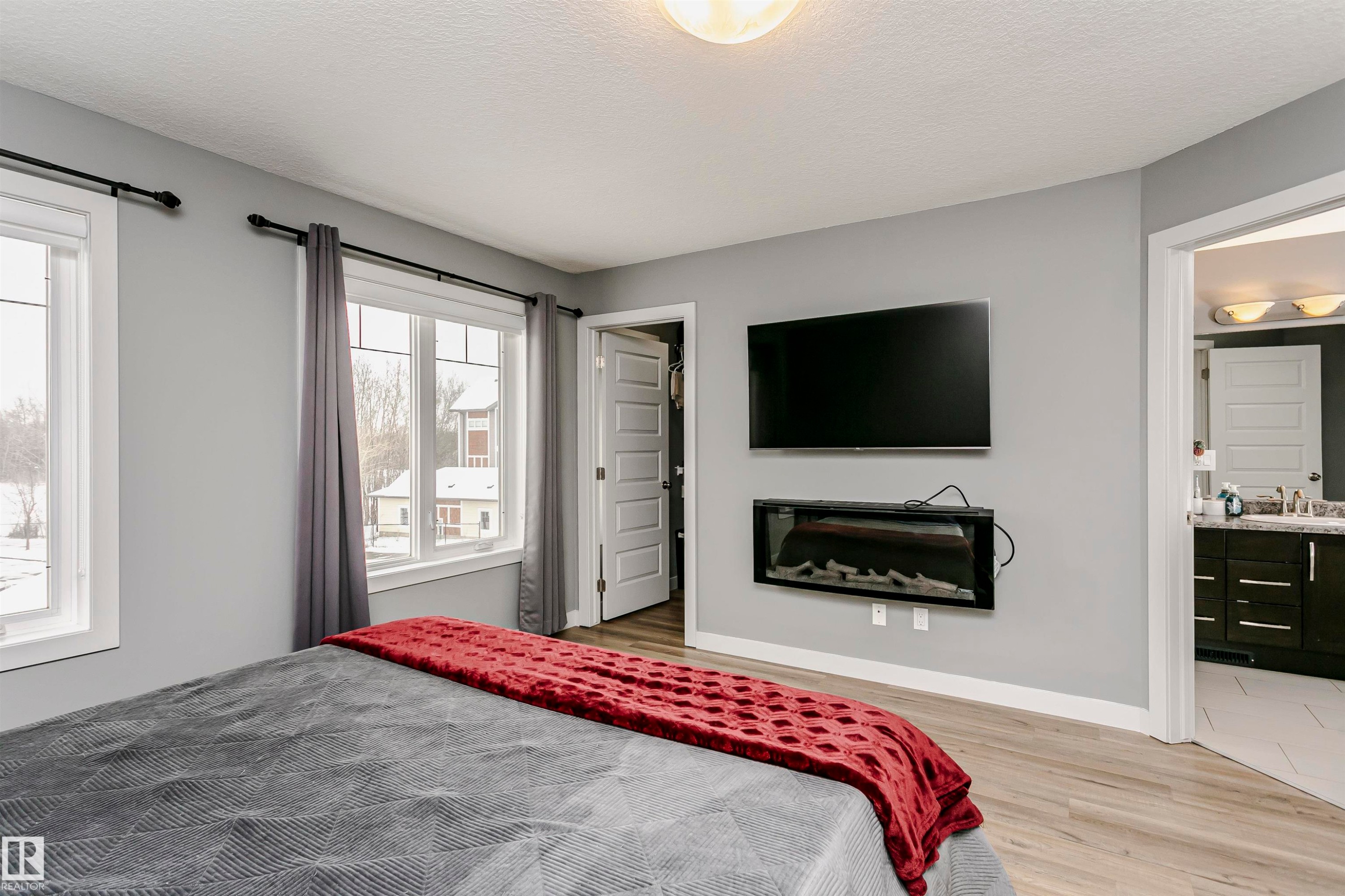 This room features light gray walls, two windows with white trim, and light wood-style flooring - 21807 97 Avenue, Edmonton, AB - Indoor Photo Showing Bedroom