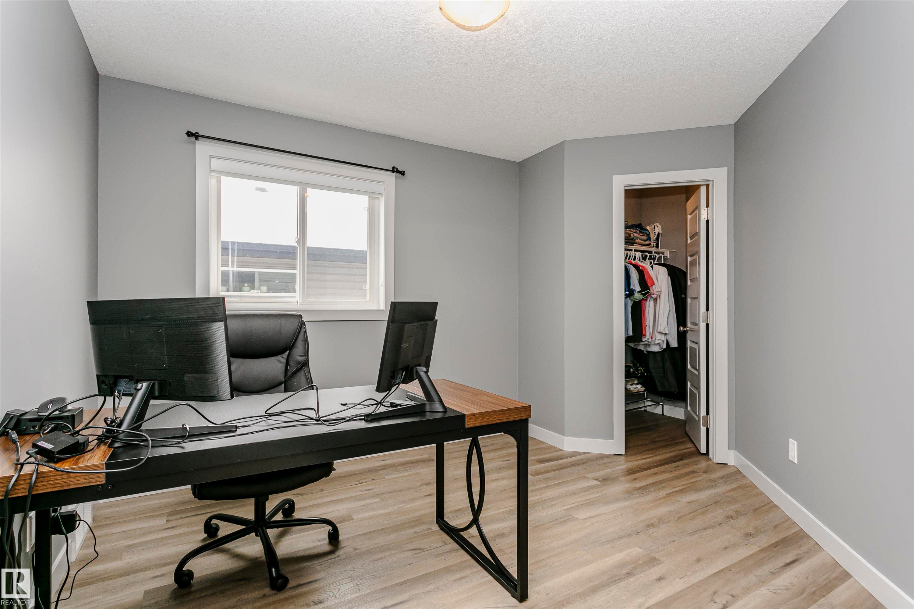 The room features light gray walls, a window with white trim, and light wood-style flooring - 21807 97 Avenue, Edmonton, AB - Indoor Photo Showing Office