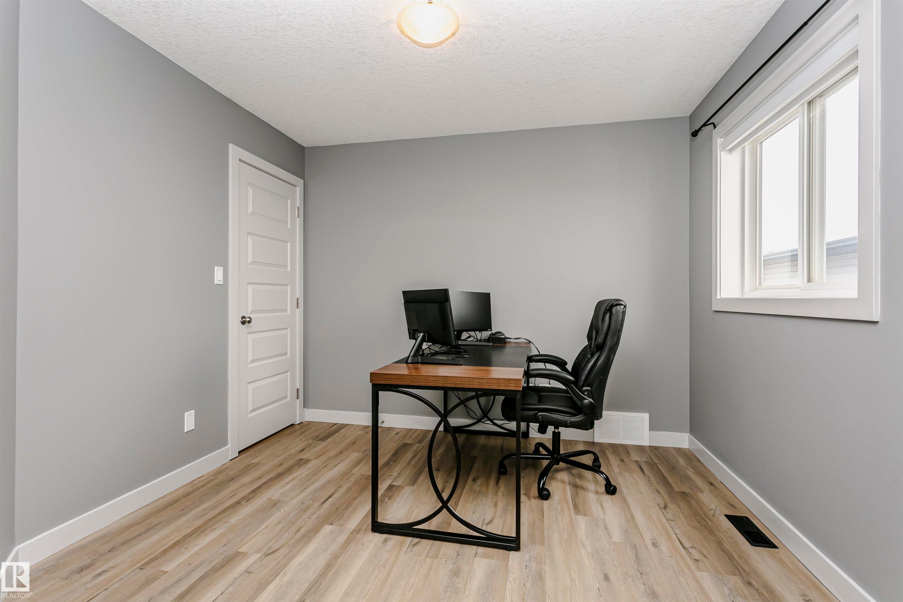 This versatile room features light-colored flooring, a window with a white frame providing natural light, and a white paneled door - 21807 97 Avenue, Edmonton, AB - Indoor Photo Showing Office