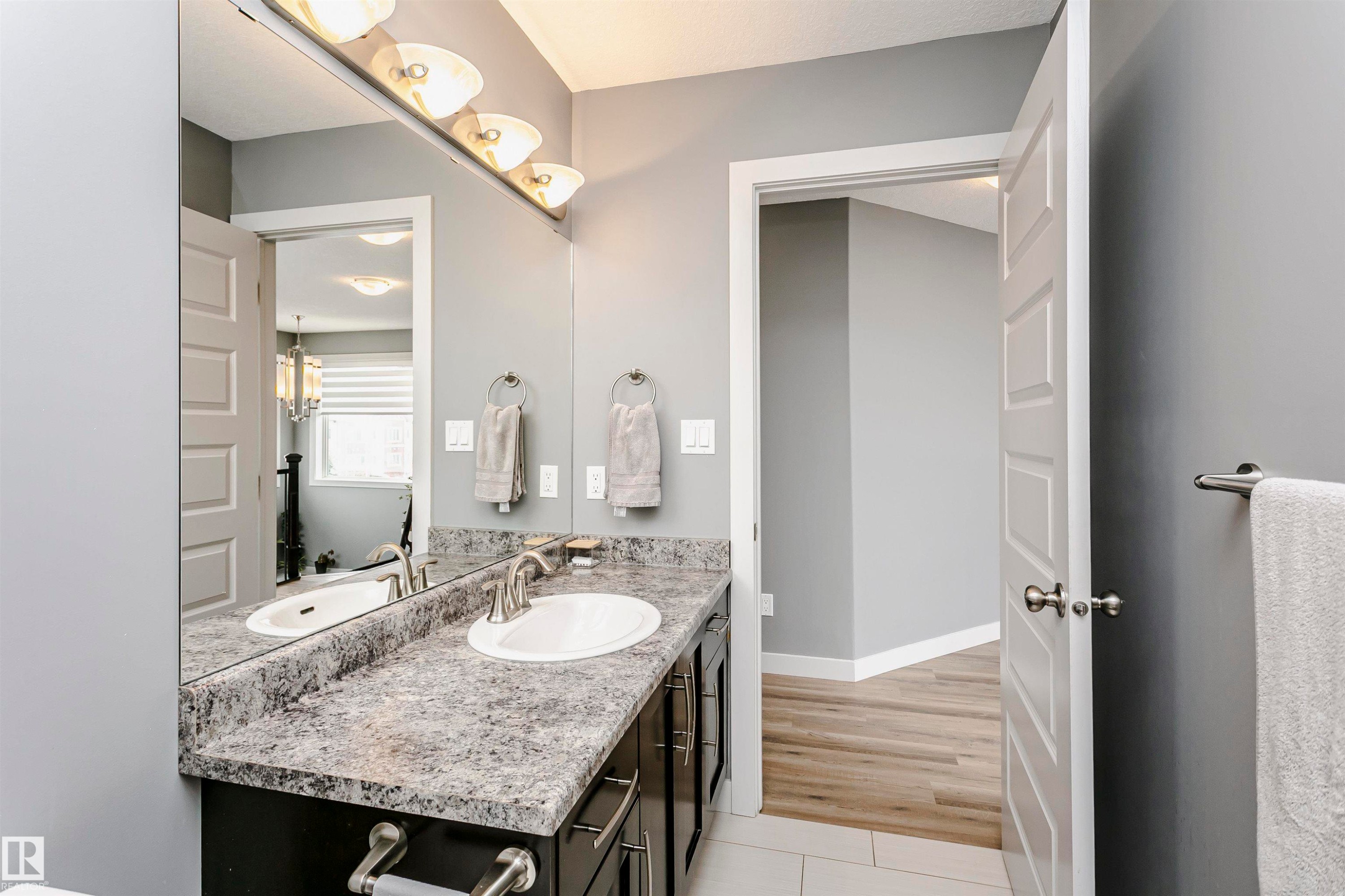 Bathroom vanity with a white oval sink, chrome faucet, and speckled gray countertop - 21807 97 Avenue, Edmonton, AB - Indoor Photo Showing Bathroom
