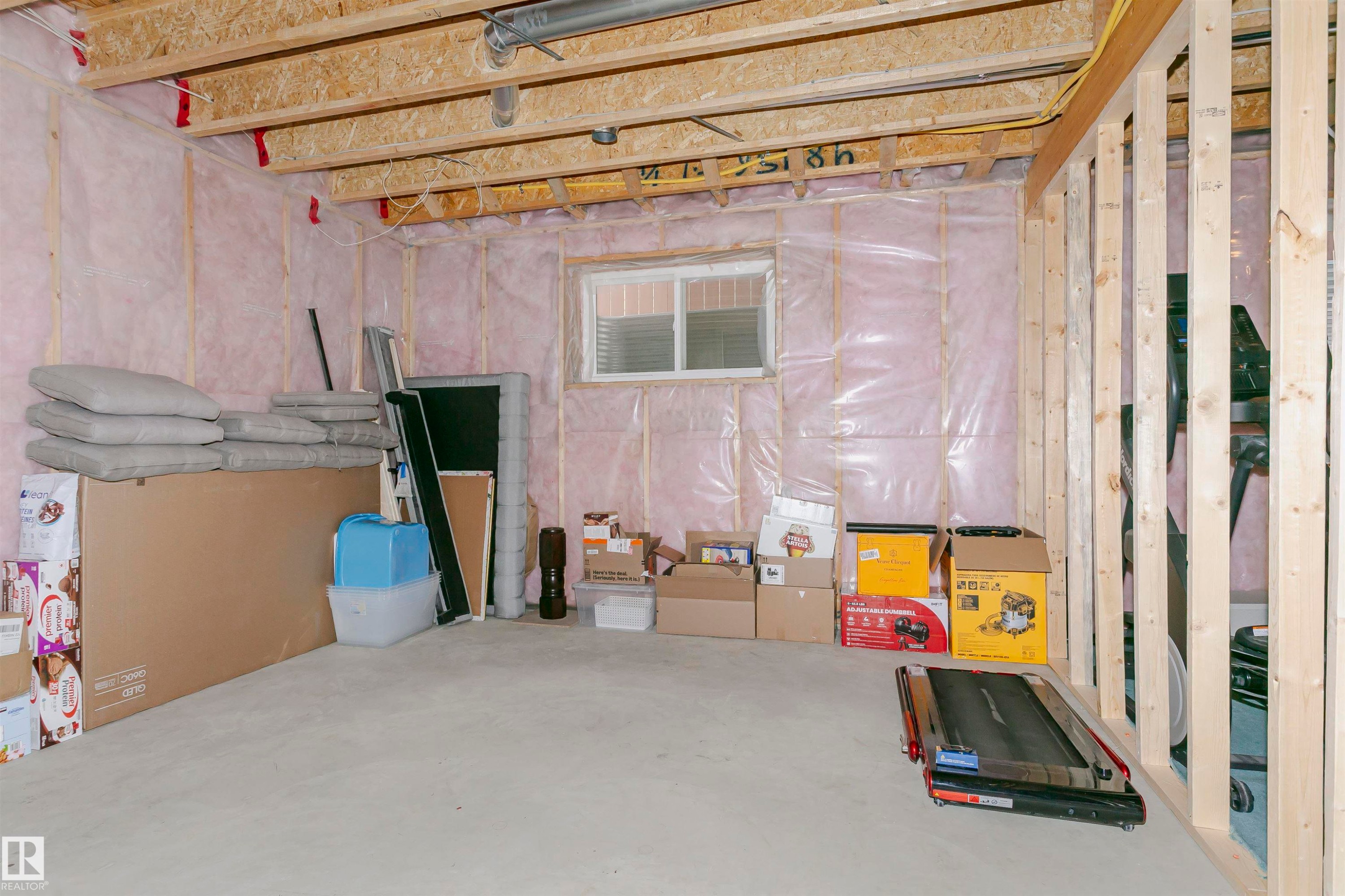 Unfinished basement space with exposed wooden joists and framing, insulated walls, concrete flooring, and a visible window - 21807 97 Avenue, Edmonton, AB - Indoor Photo Showing Basement