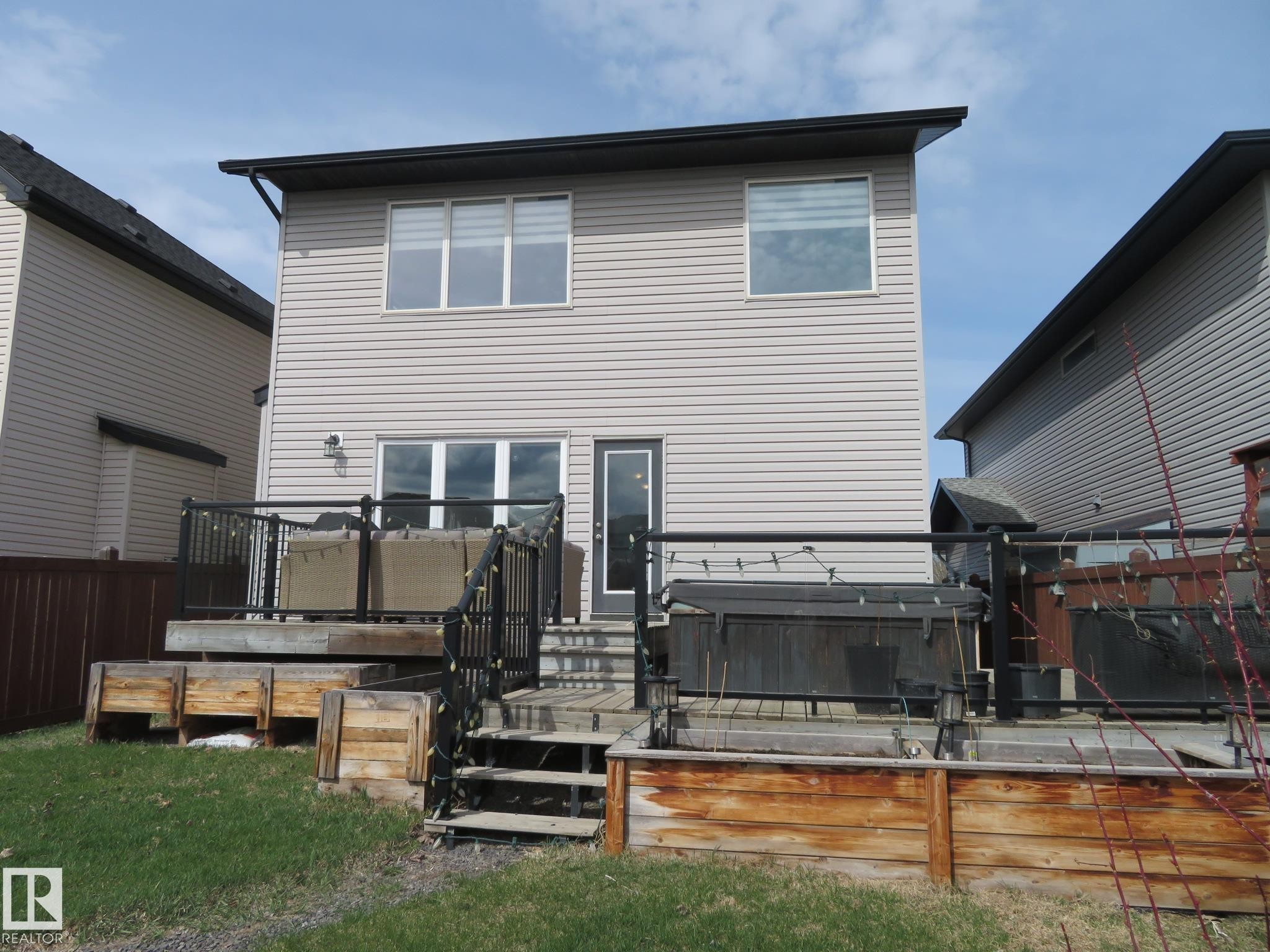 Rear elevation featuring light-colored siding and a multi-level wood deck - 21807 97 Avenue, Edmonton, AB - Outdoor With Deck Patio Veranda With Exterior
