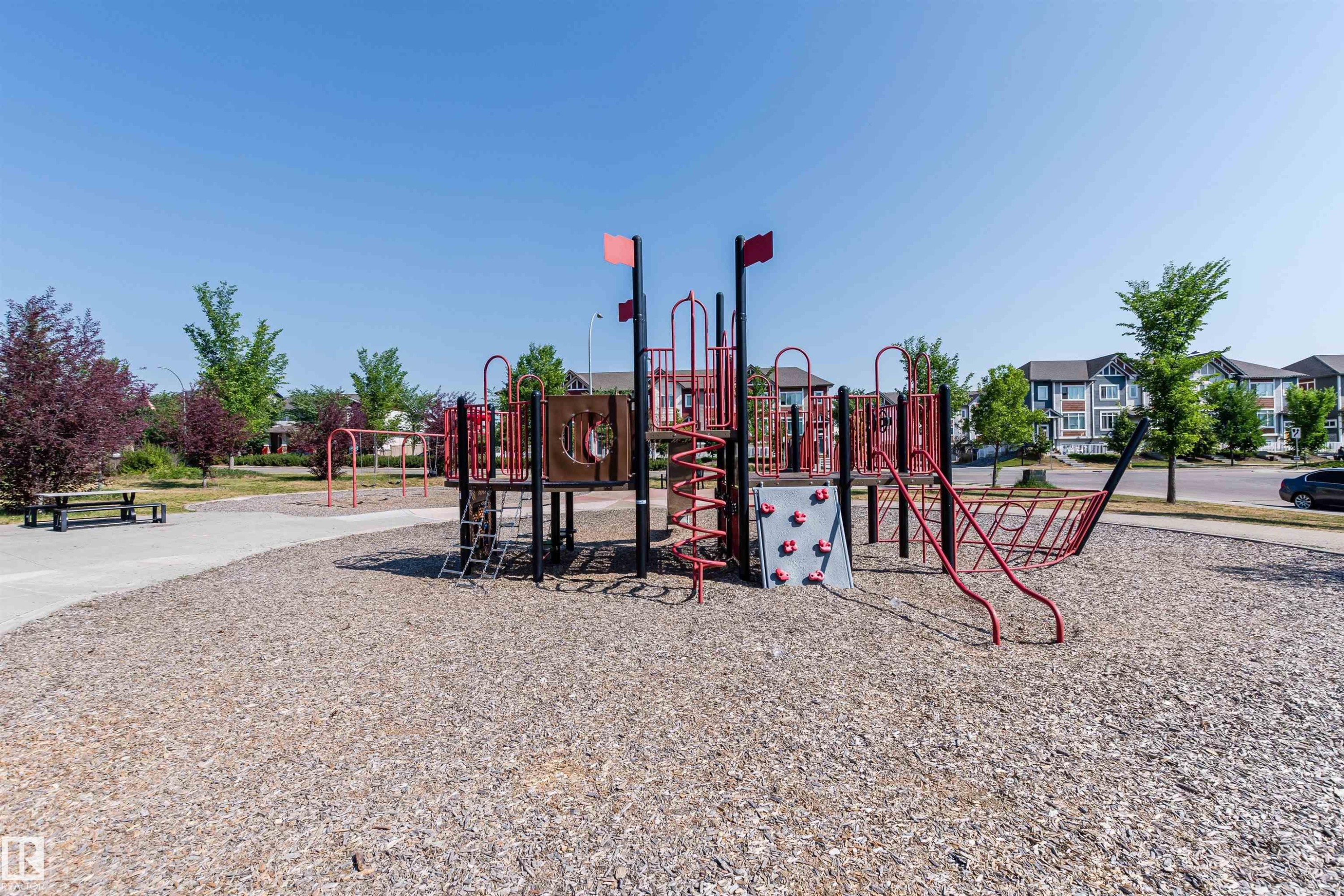 Community park featuring a play structure with slides and climbing elements, surrounded by wood chip ground cover - 21807 97 Avenue, Edmonton, AB - Outdoor