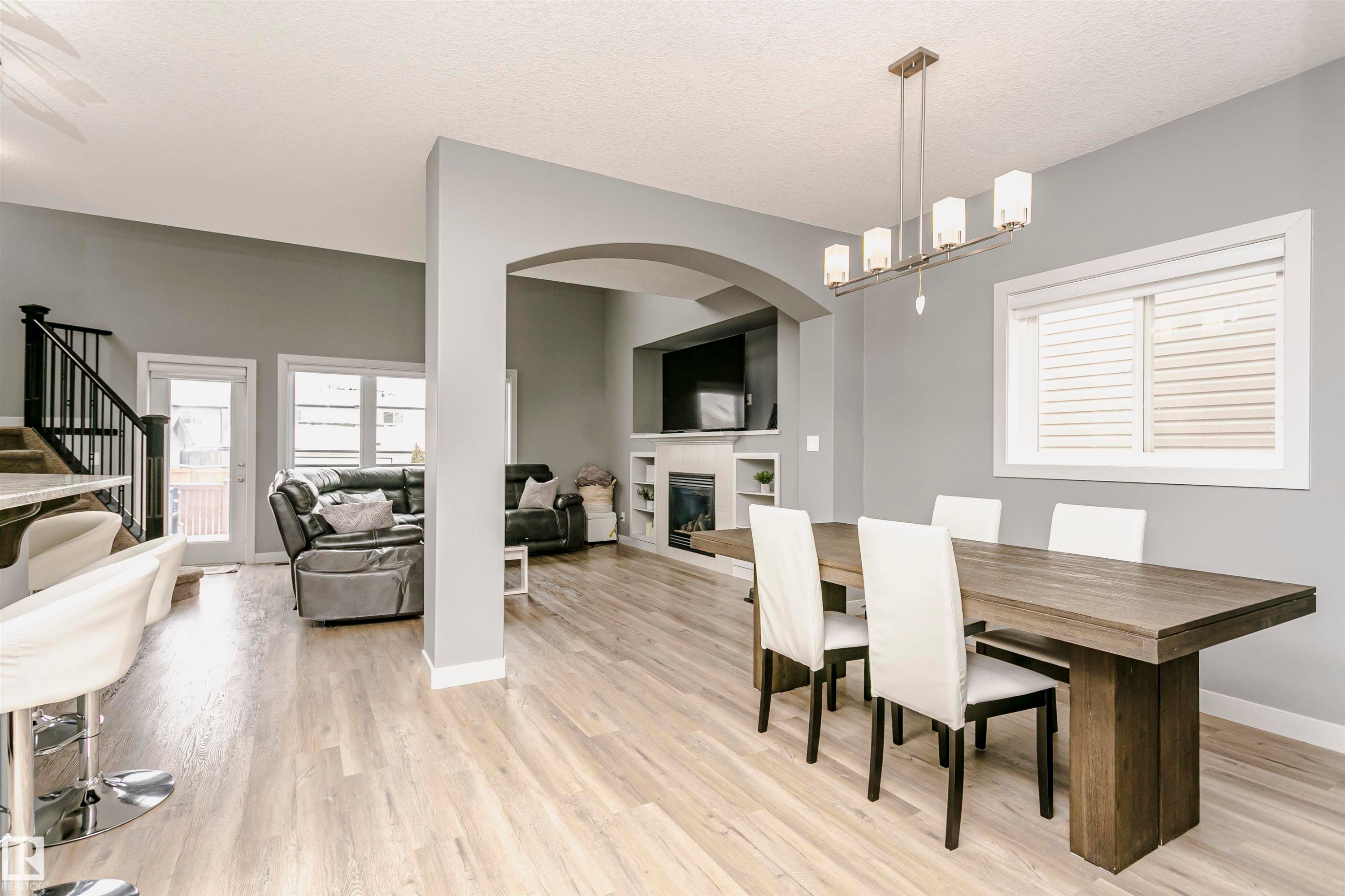 Open concept living space featuring light-toned flooring, an arched entryway, and a dining area with a modern chandelier - 21807 97 Avenue, Edmonton, AB - Indoor