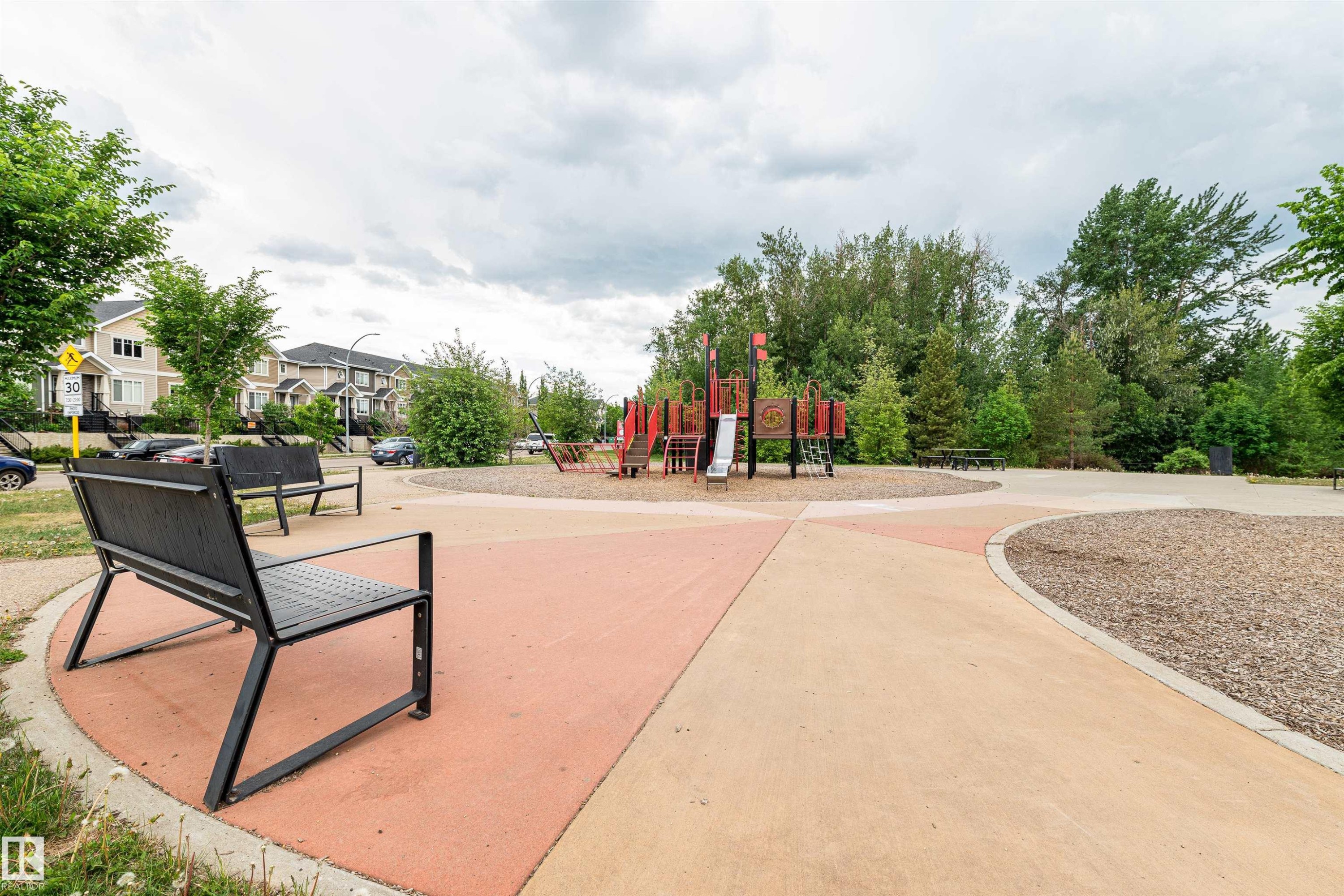 Community park area featuring a playground structure, benches, and paved pathways, with residential properties visible in the background - 21807 97 Avenue, Edmonton, AB - Outdoor