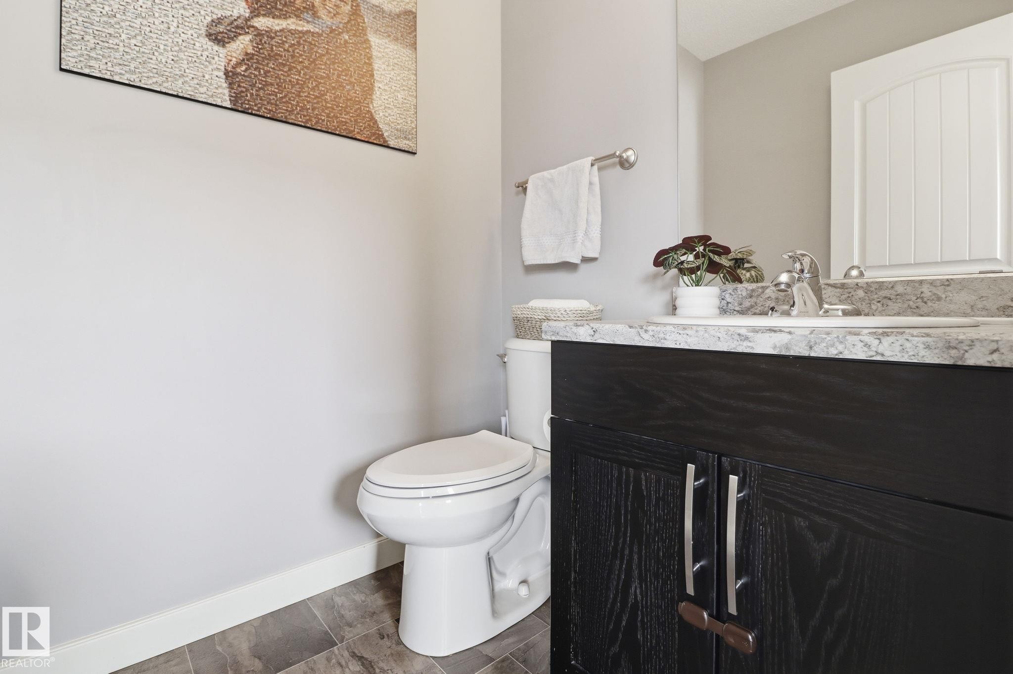 The bathroom features a white toilet, a dark wood vanity with a light-colored countertop, and a white sink with a chrome faucet - 430 Watt Boulevard, Edmonton, AB - Indoor Photo Showing Bathroom