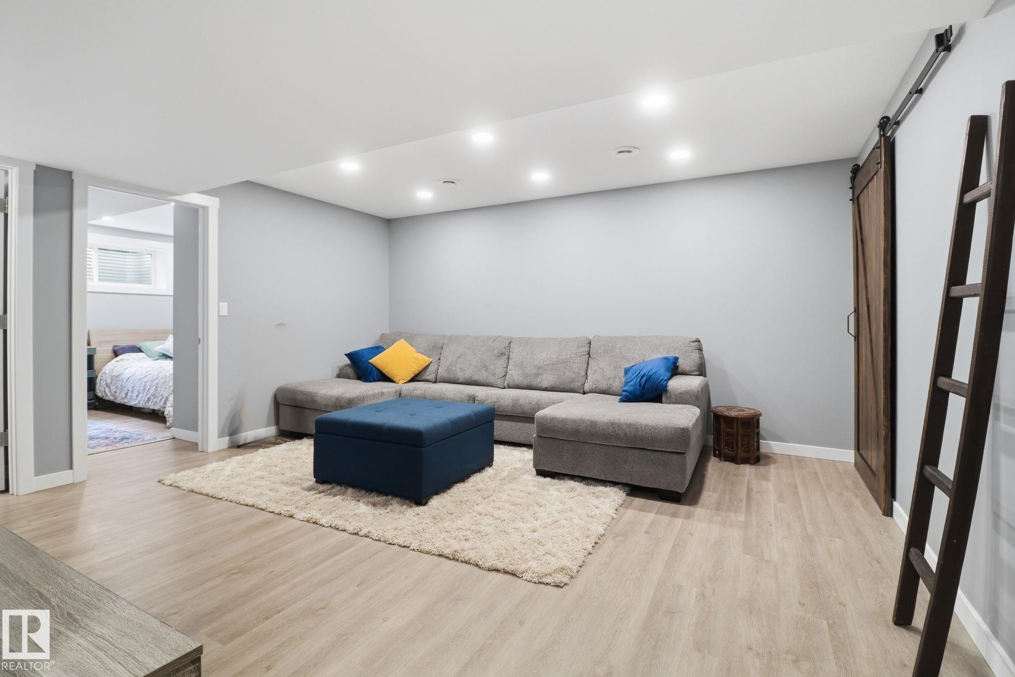 This versatile living space features light-colored flooring, recessed lighting, and a modern barn door - 430 Watt Boulevard, Edmonton, AB - Indoor Photo Showing Basement