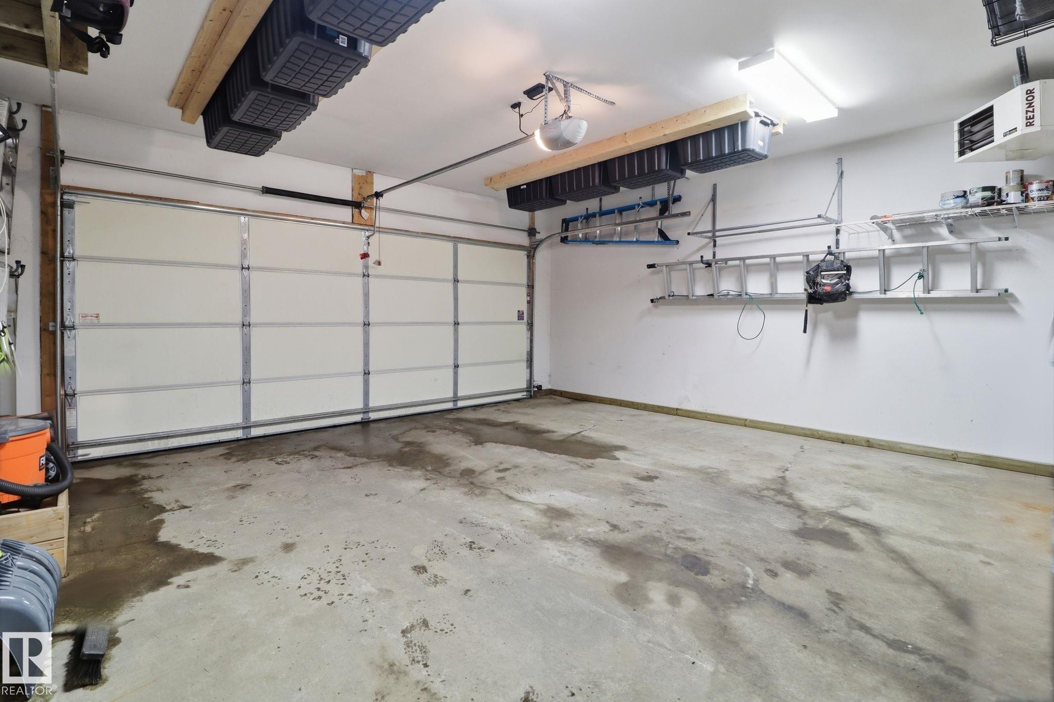 The property includes a spacious garage with a large white sectional garage door and a concrete floor - 430 Watt Boulevard, Edmonton, AB - Indoor Photo Showing Garage