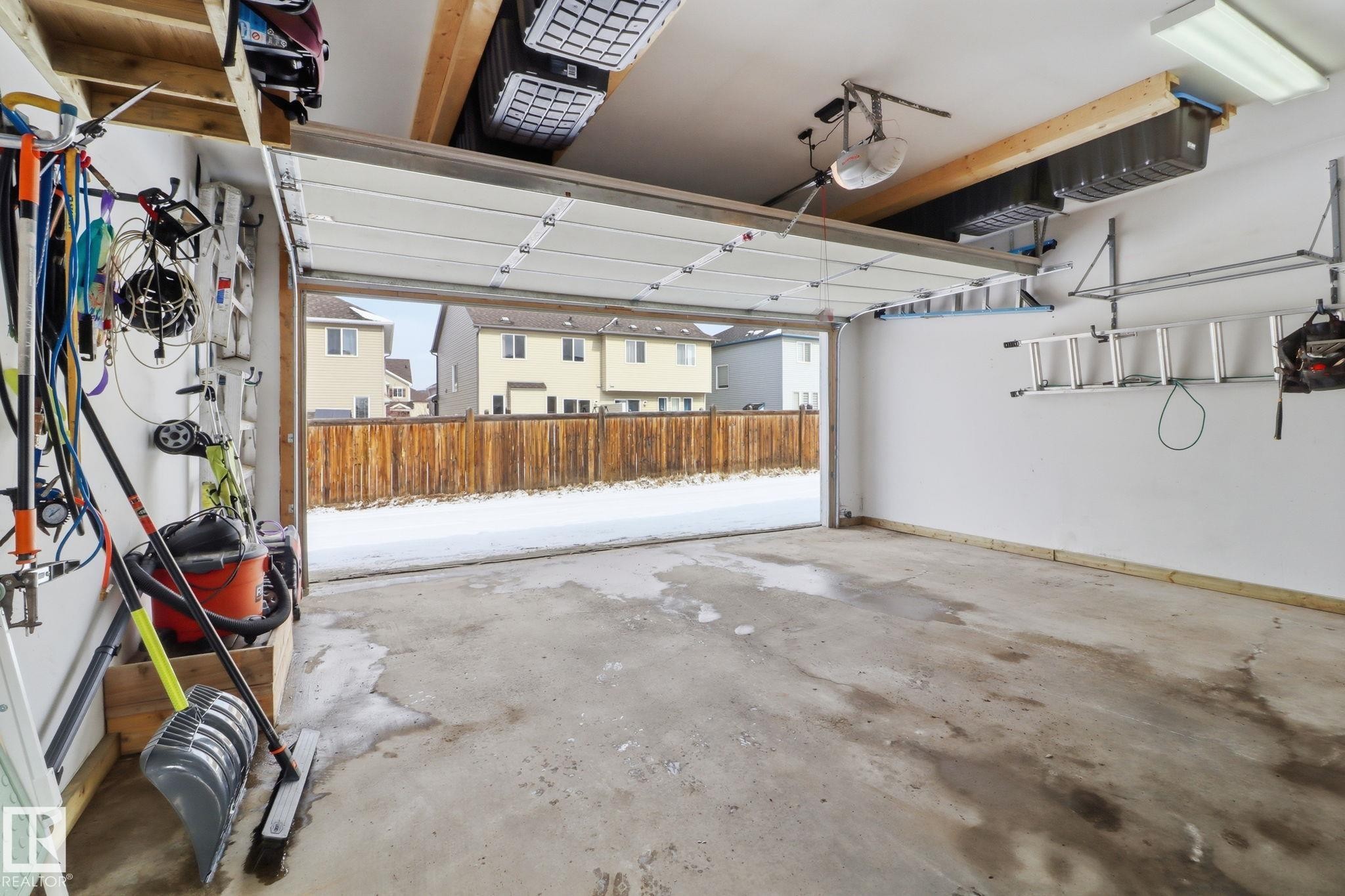 The property features an attached garage with a concrete floor, a white garage door, and overhead lighting - 430 Watt Boulevard, Edmonton, AB - Indoor Photo Showing Garage