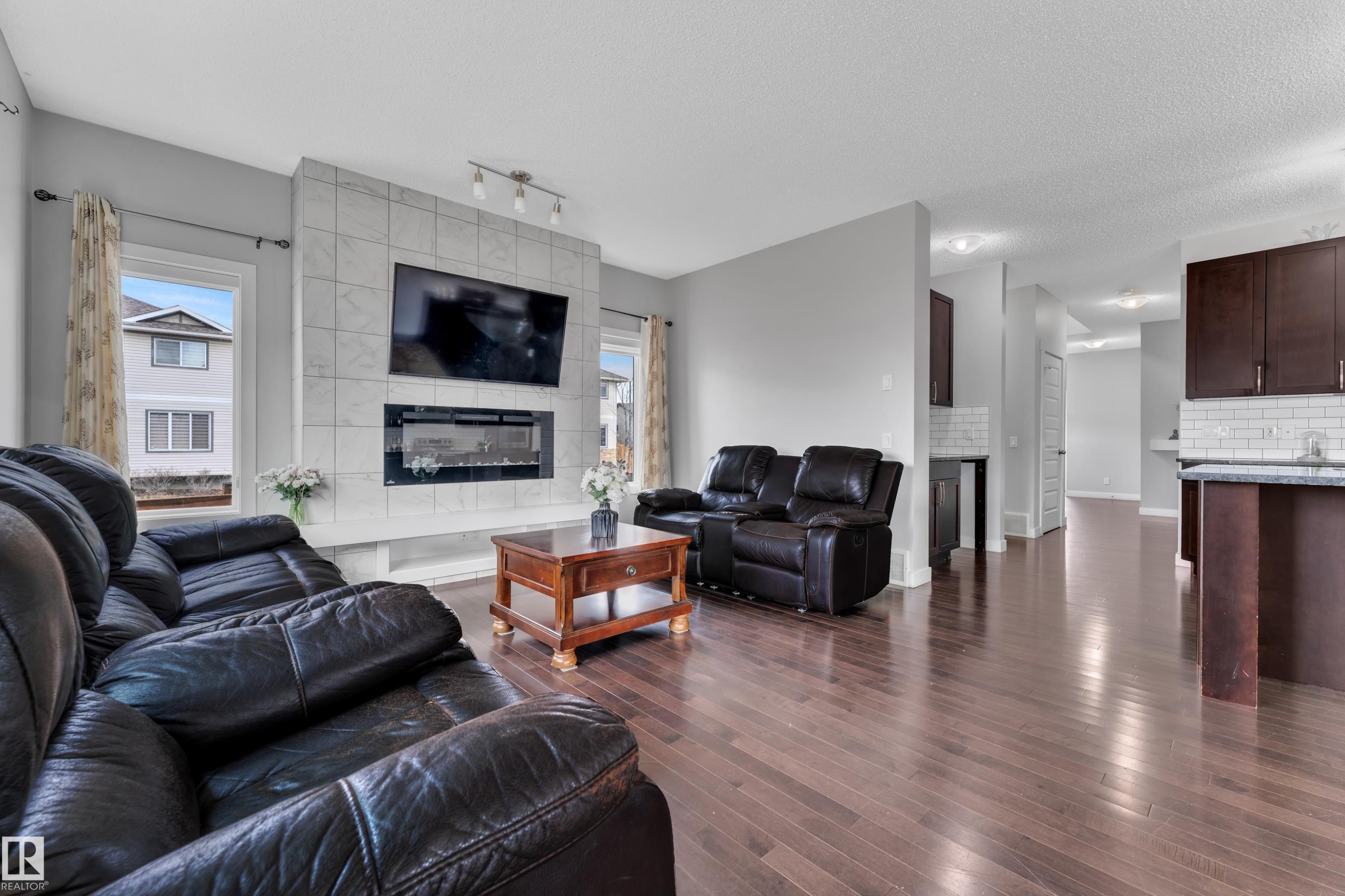 The living area features hard flooring, light gray walls, and an electric fireplace with a tiled surround - 1452 30 Street, Edmonton, AB - Indoor Photo Showing Living Room With Fireplace