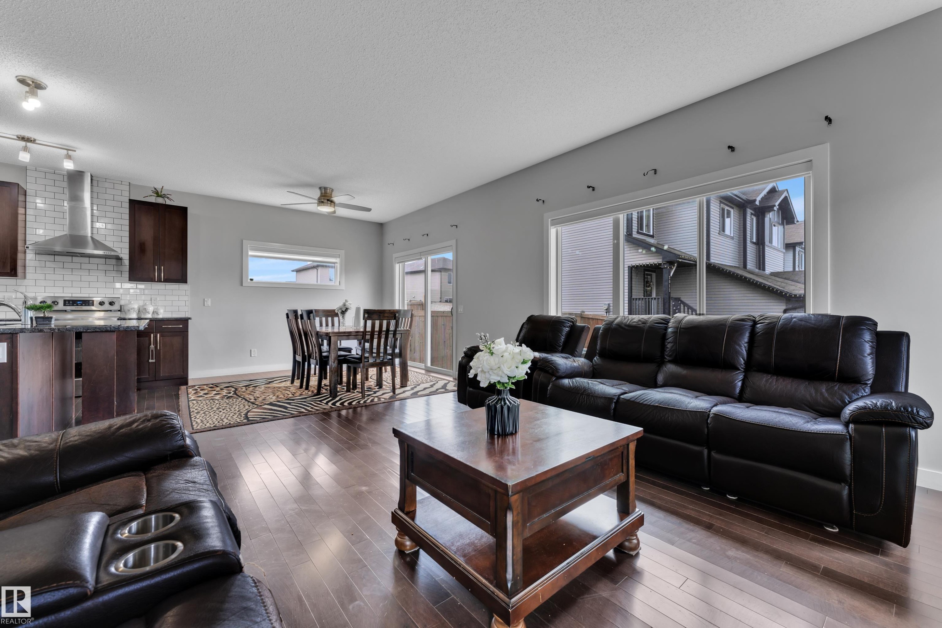 Open concept living area featuring hardwood flooring, a large window, and a sliding glass door providing access to the outdoors - 1452 30 Street, Edmonton, AB - Indoor Photo Showing Living Room