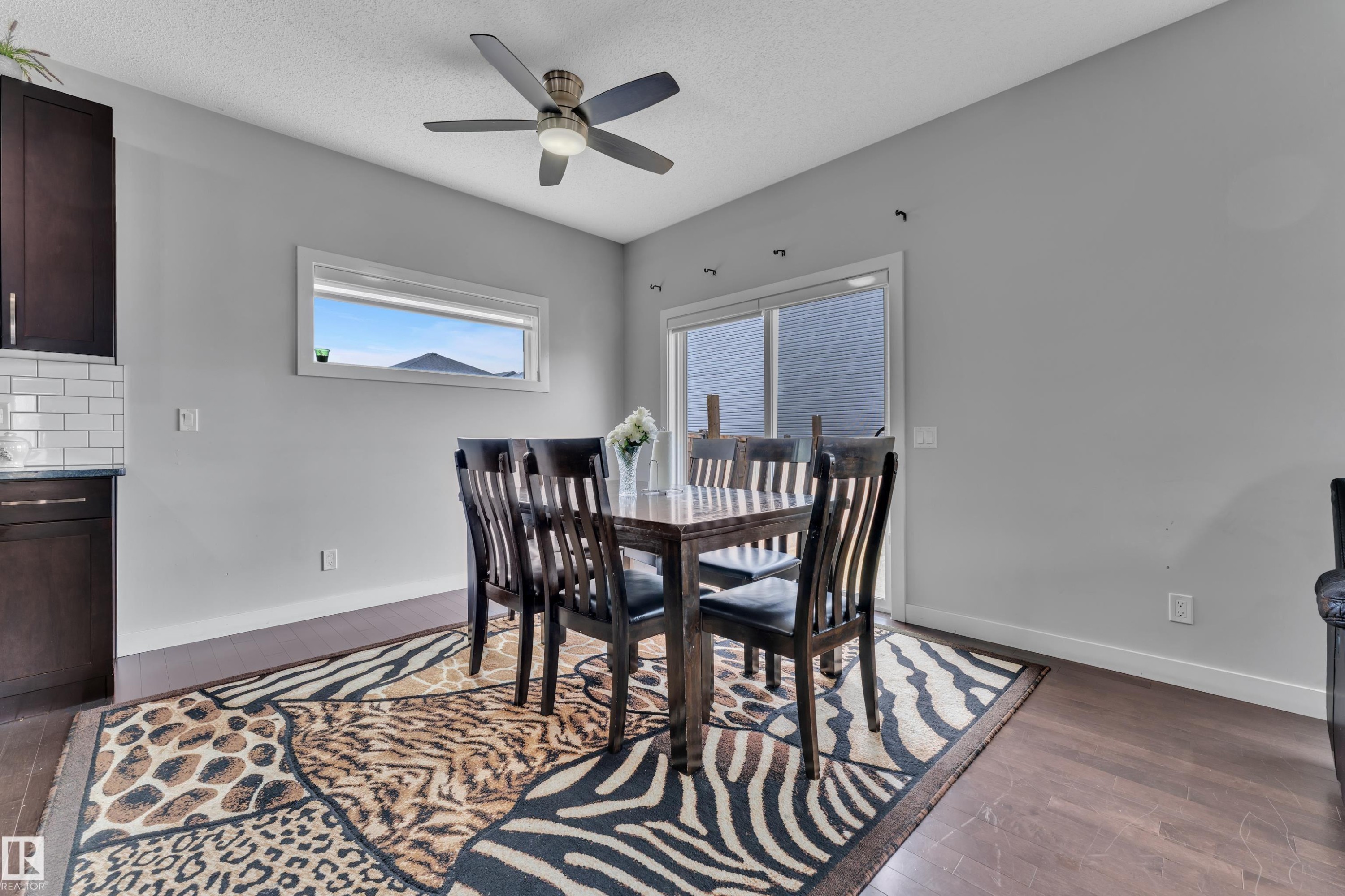 Dining area featuring hardwood floors, a ceiling fan, a window, and sliding glass doors - 1452 30 Street, Edmonton, AB - Indoor Photo Showing Dining Room