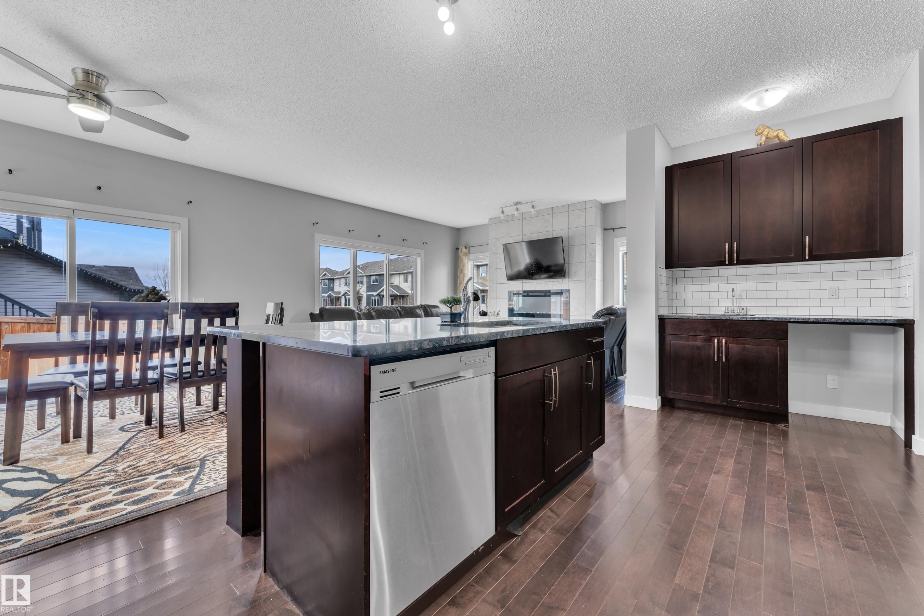The kitchen features dark wood cabinetry, a central island with a dishwasher, and a sink - 1452 30 Street, Edmonton, AB - Indoor Photo Showing Kitchen