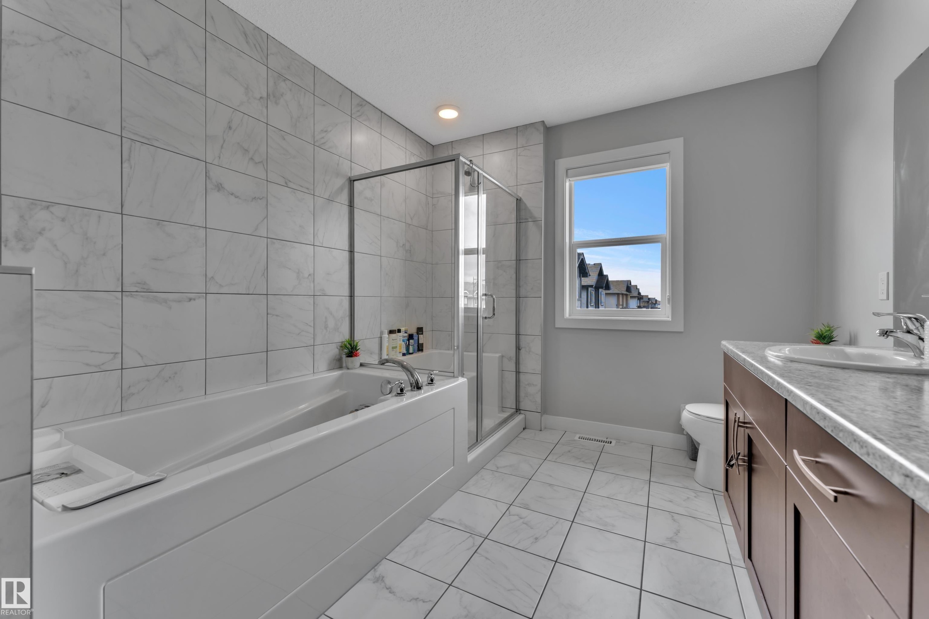 Bathroom featuring a white bathtub, a glass-enclosed shower, and a vanity with a double sink - 1452 30 Street, Edmonton, AB - Indoor Photo Showing Bathroom