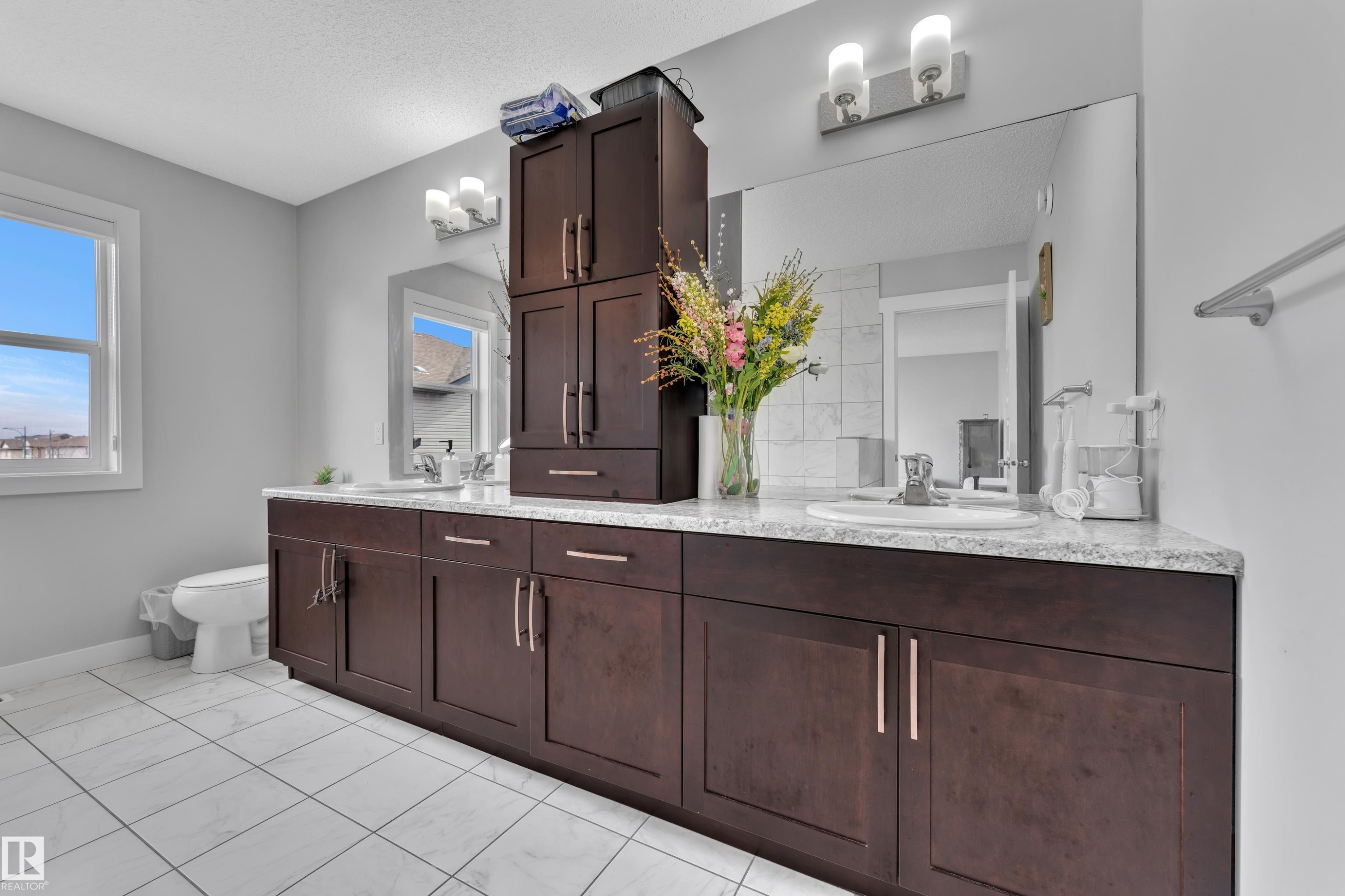 The bathroom features a long vanity with dark wood cabinetry, a light-colored countertop, and dual sinks - 1452 30 Street, Edmonton, AB - Indoor Photo Showing Bathroom