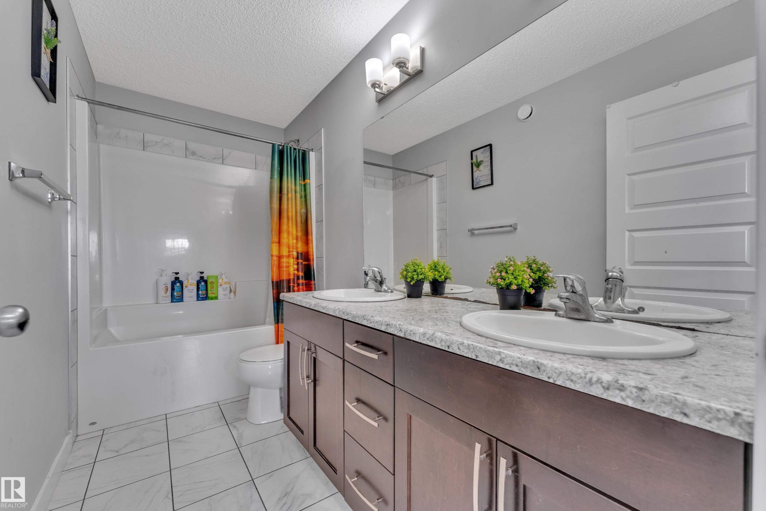 This bathroom features a double vanity with two sinks and a spacious mirror, complemented by a bathtub with a shower - 1452 30 Street, Edmonton, AB - Indoor Photo Showing Bathroom