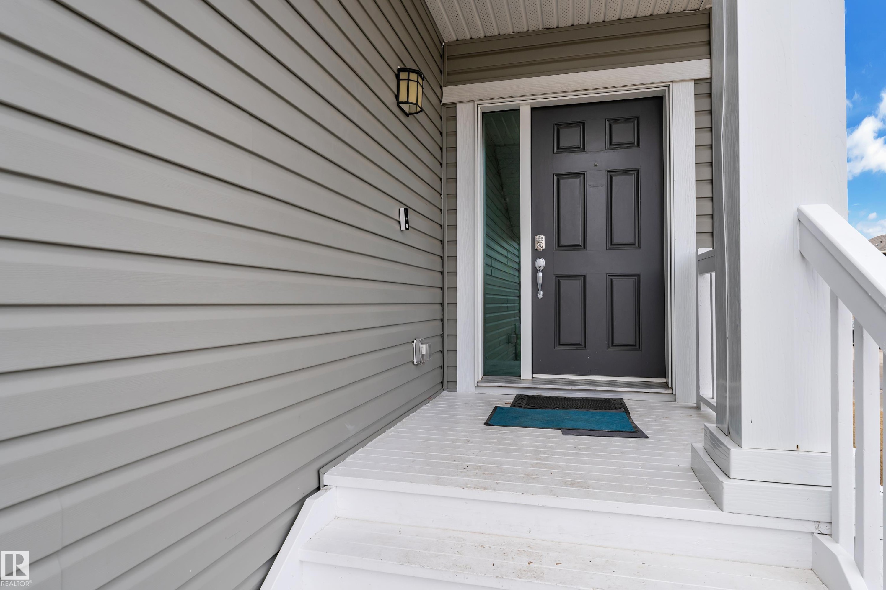 The property features an inviting entrance with light gray siding, a dark paneled front door, and a white porch with railings - 1452 30 Street, Edmonton, AB - Outdoor With Exterior