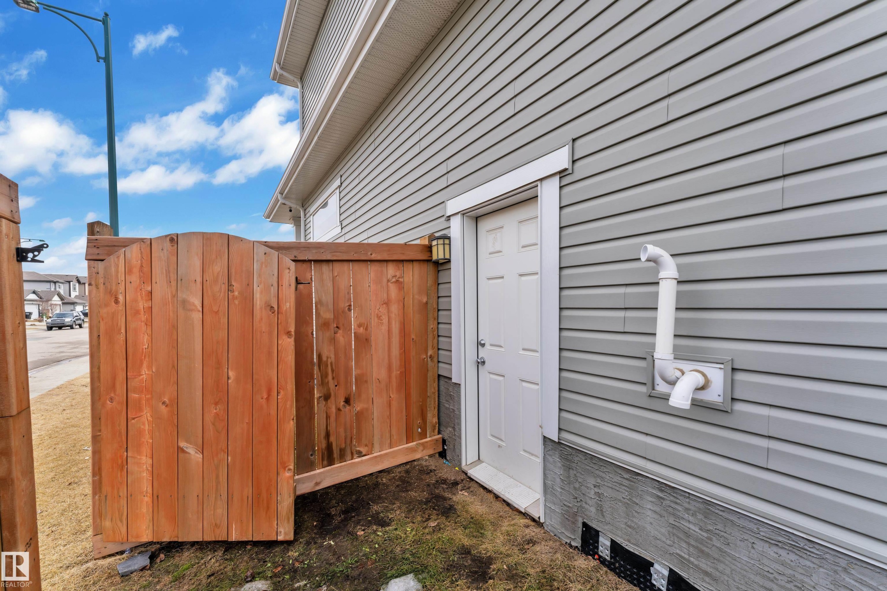 The property features grey horizontal siding, a white exterior door, and a brown wooden fence - 1452 30 Street, Edmonton, AB - Outdoor With Exterior