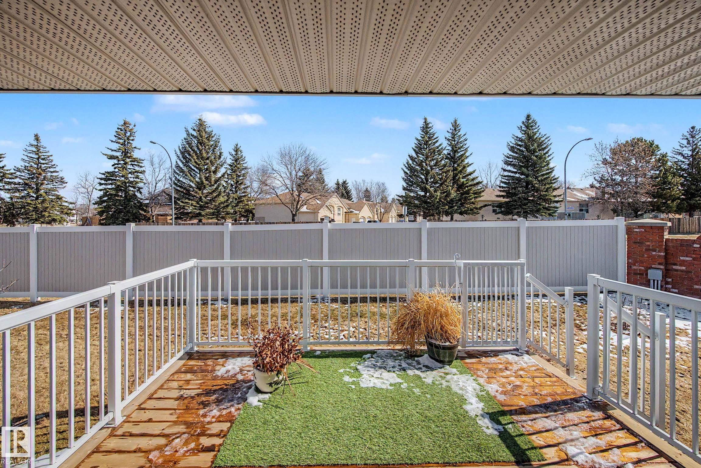 The property features a patio area with white railings and a partial artificial turf covering - 21 1850 Mill Woods Road E, Edmonton, AB - Outdoor With Deck Patio Veranda