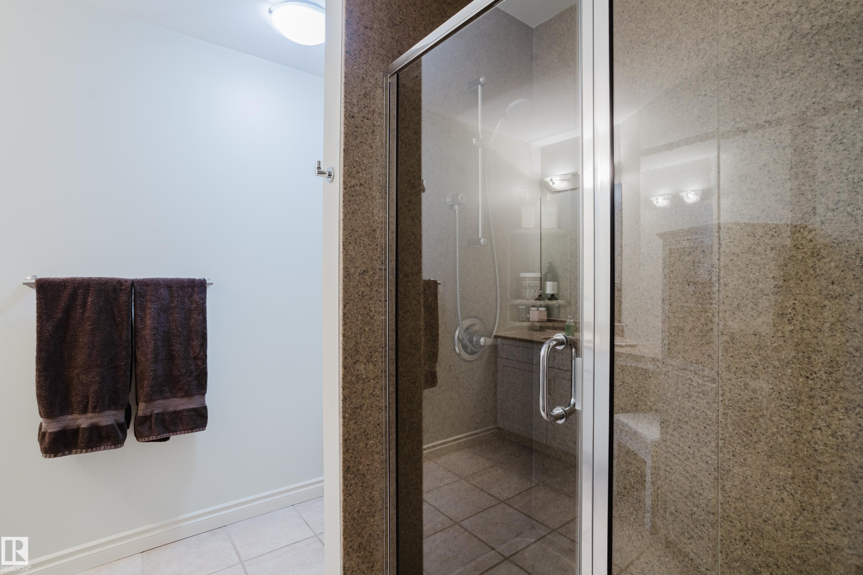 The bathroom features a glass-enclosed shower with stone-look tile walls and a tiled floor - 206 10108 125 Street, Edmonton, AB - Indoor Photo Showing Bathroom